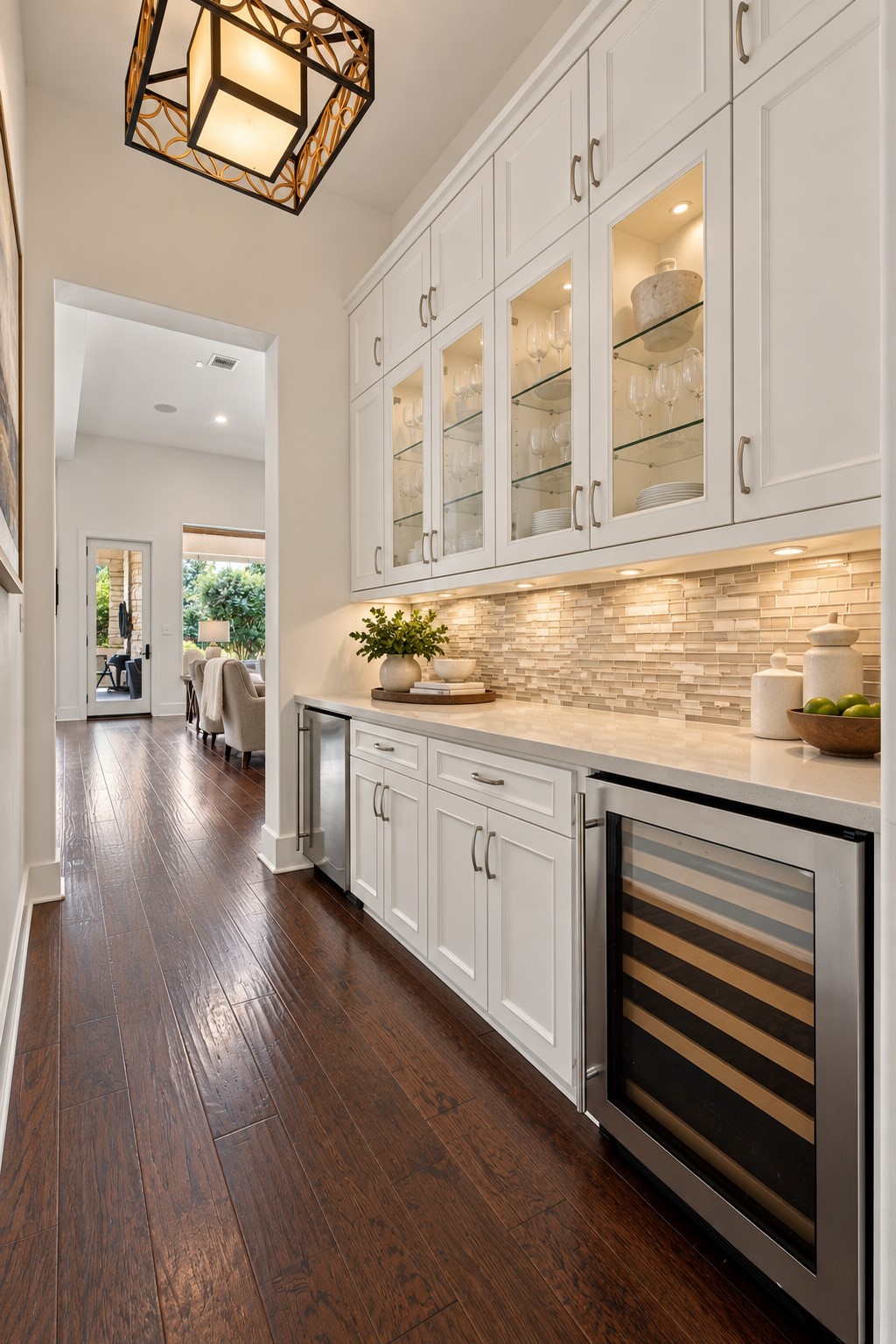 Elegant butlers pantry and beverage center featuring custom cabinetry, glass-front displays, generous counter space, and built-in beverage refrigeration.