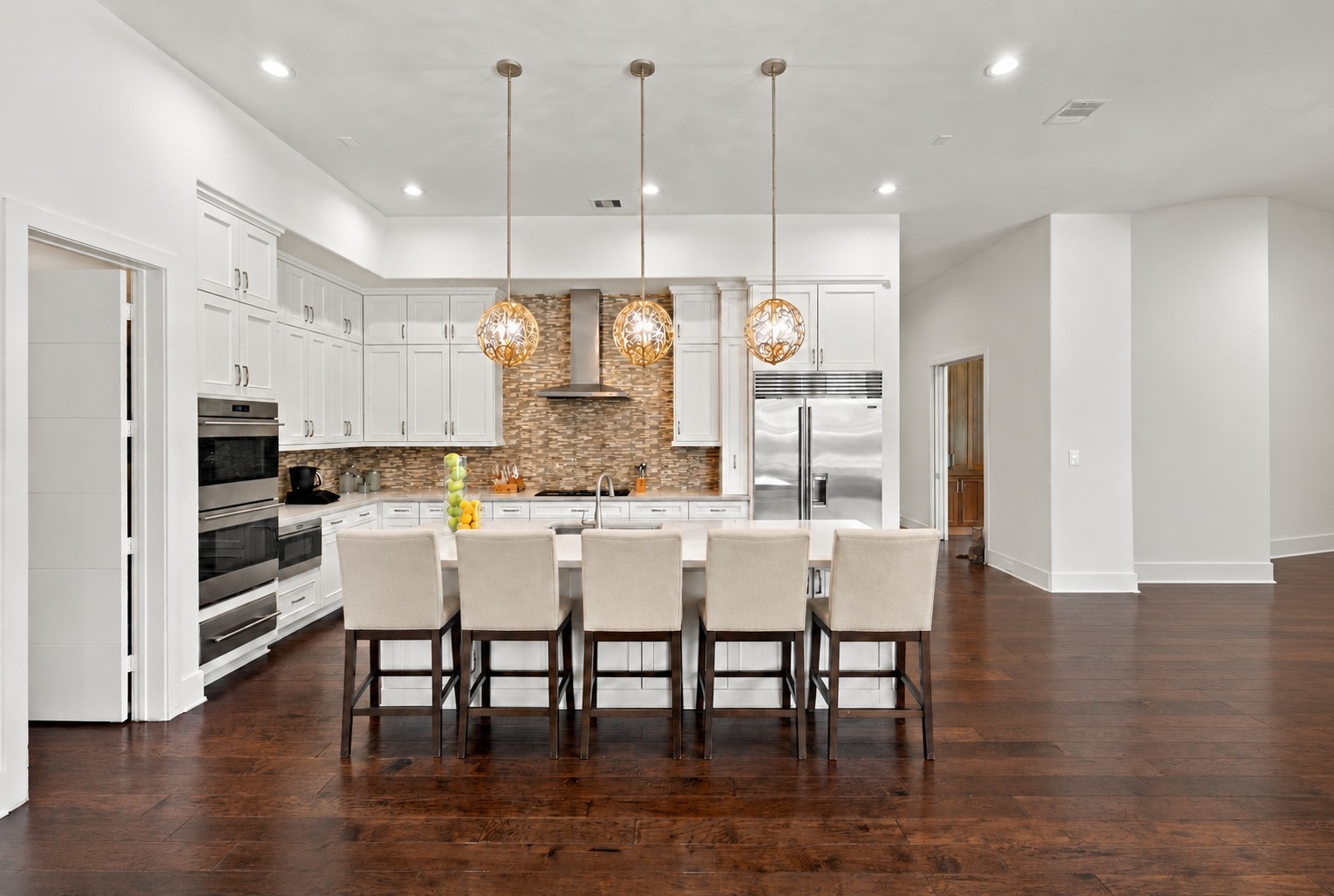 Gourmet kitchen featuring a spacious center island, elegant pendant lighting, custom cabinetry, and premium stainless steel appliances.