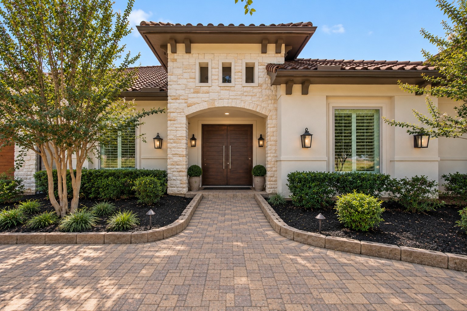 Grand entrance featuring striking stone architecture, elegant double doors, and beautifully manicured landscaping, creating an impressive welcome to this luxury estate.