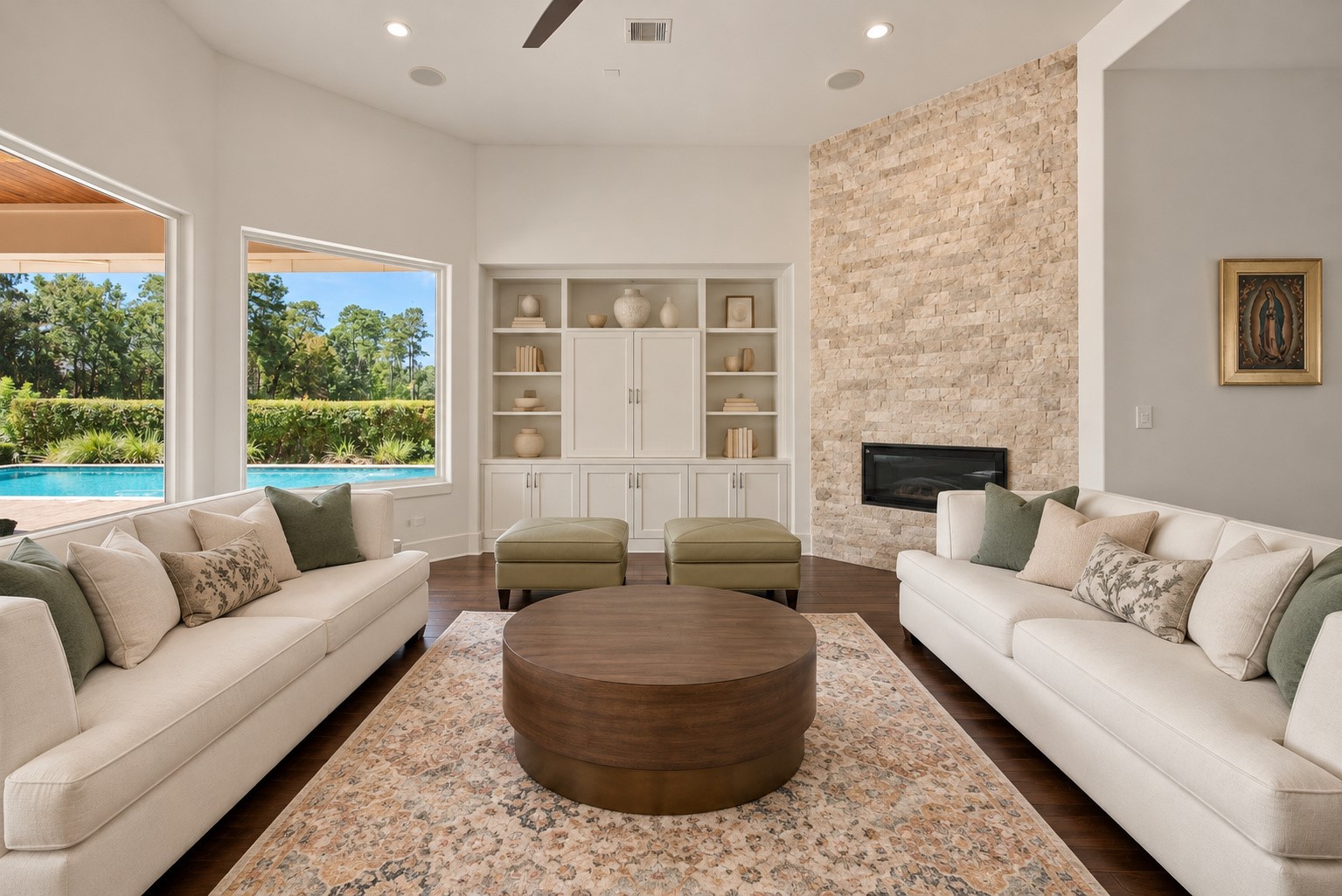 Picturesque living room featuring a stunning stone fireplace, elegant finishes, and expansive windows overlooking the resort-style pool and covered patio.