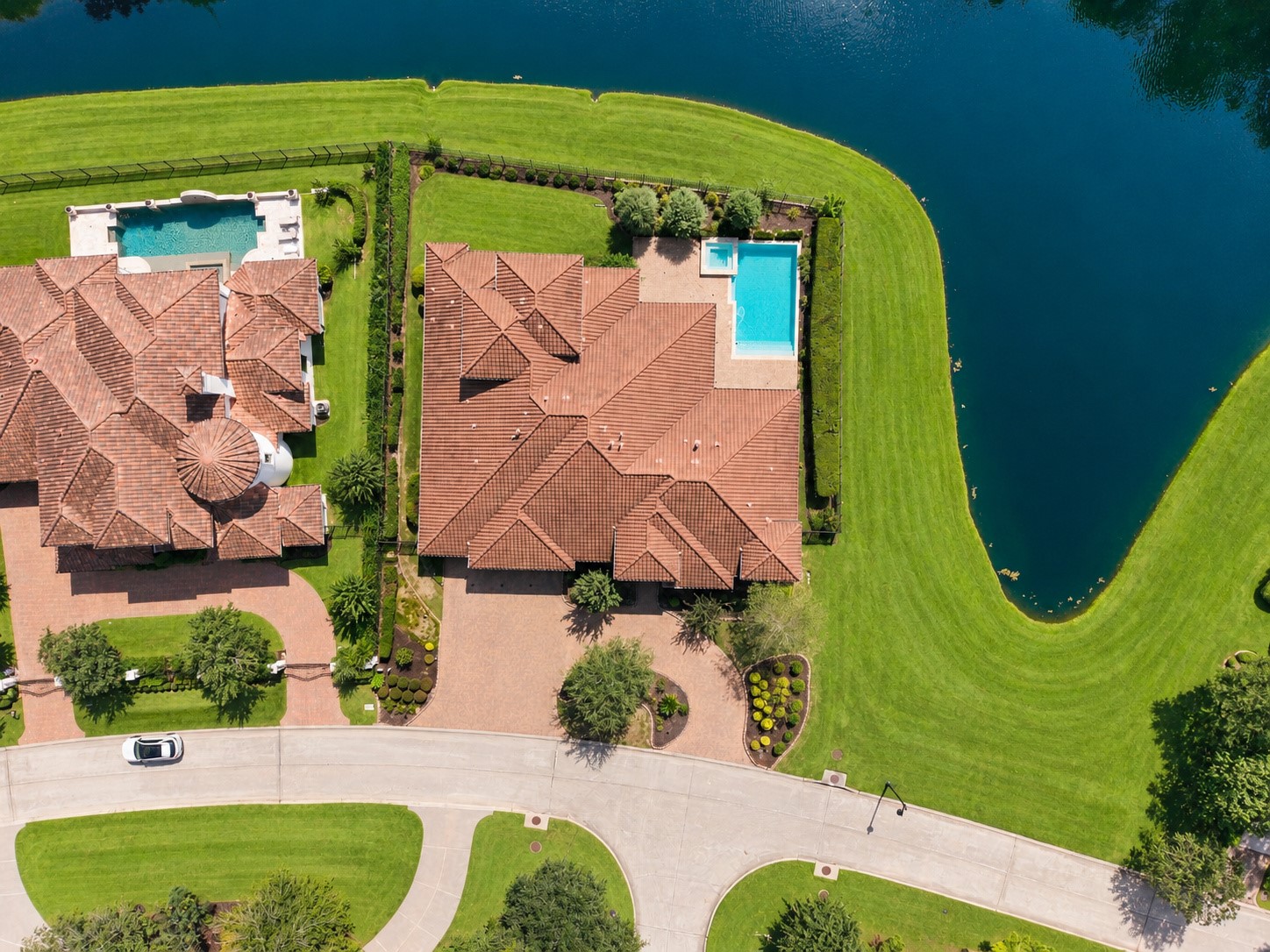 overhead view showcasing the estate's expansive footprint, resort-style pool, and exceptional waterfront setting surrounded by lush green space.