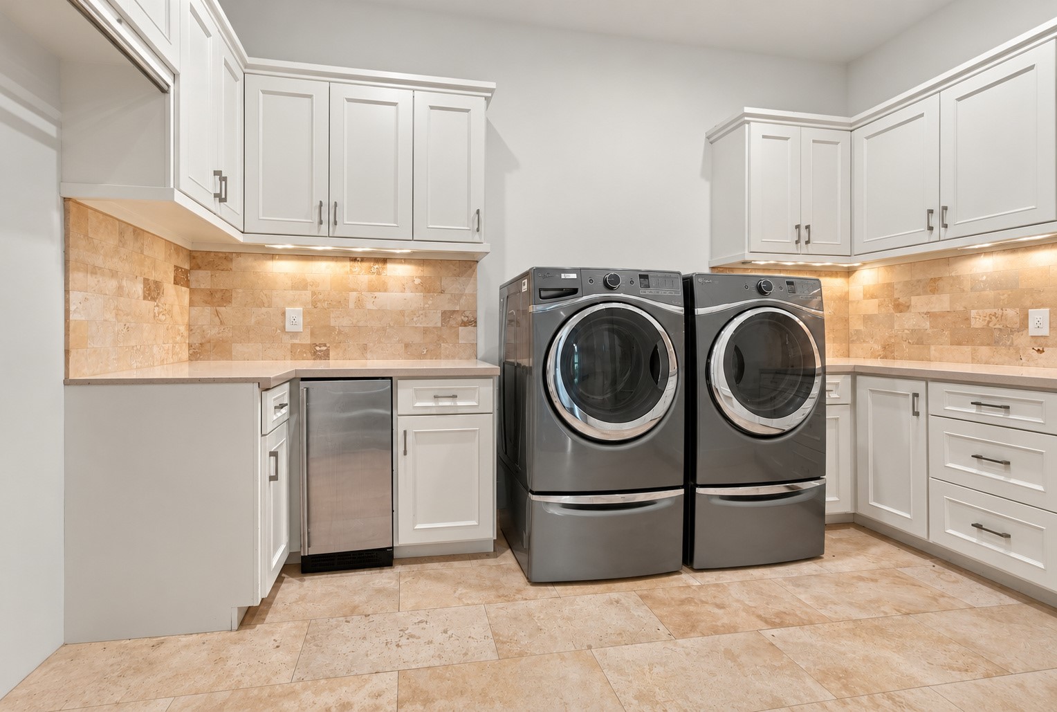 Spacious utility room featuring abundant custom cabinetry, generous counter space, and full-size washer and dryer, combining luxury with everyday functionality.