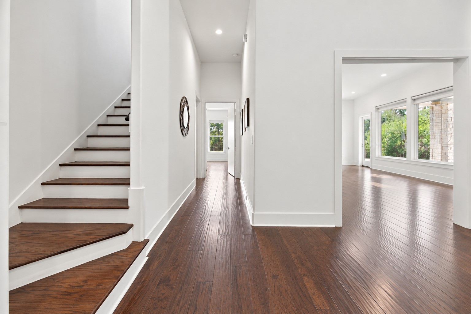 Inviting entry hallway featuring rich hardwood floors, a beautiful staircase, and an open layout filled with natural light.