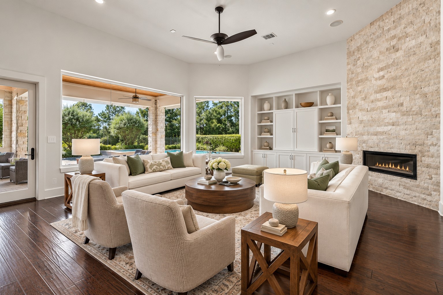 Picturesque living room featuring a stunning stone fireplace, elegant finishes, and expansive windows overlooking the resort-style pool and covered patio.