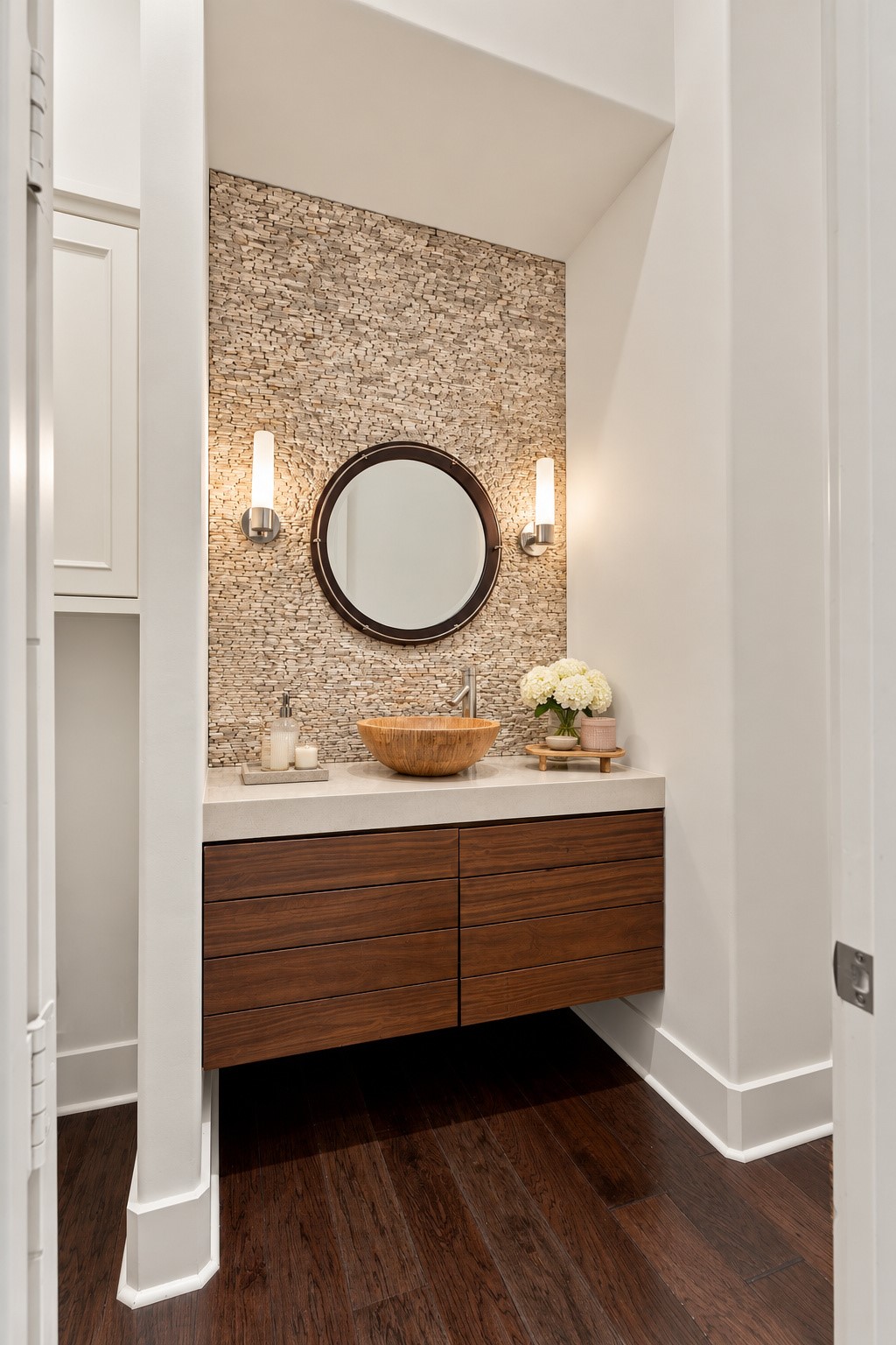 Elegant half bath featuring a floating wood vanity, vessel sink, designer lighting, and a beautiful textured stone accent wall.