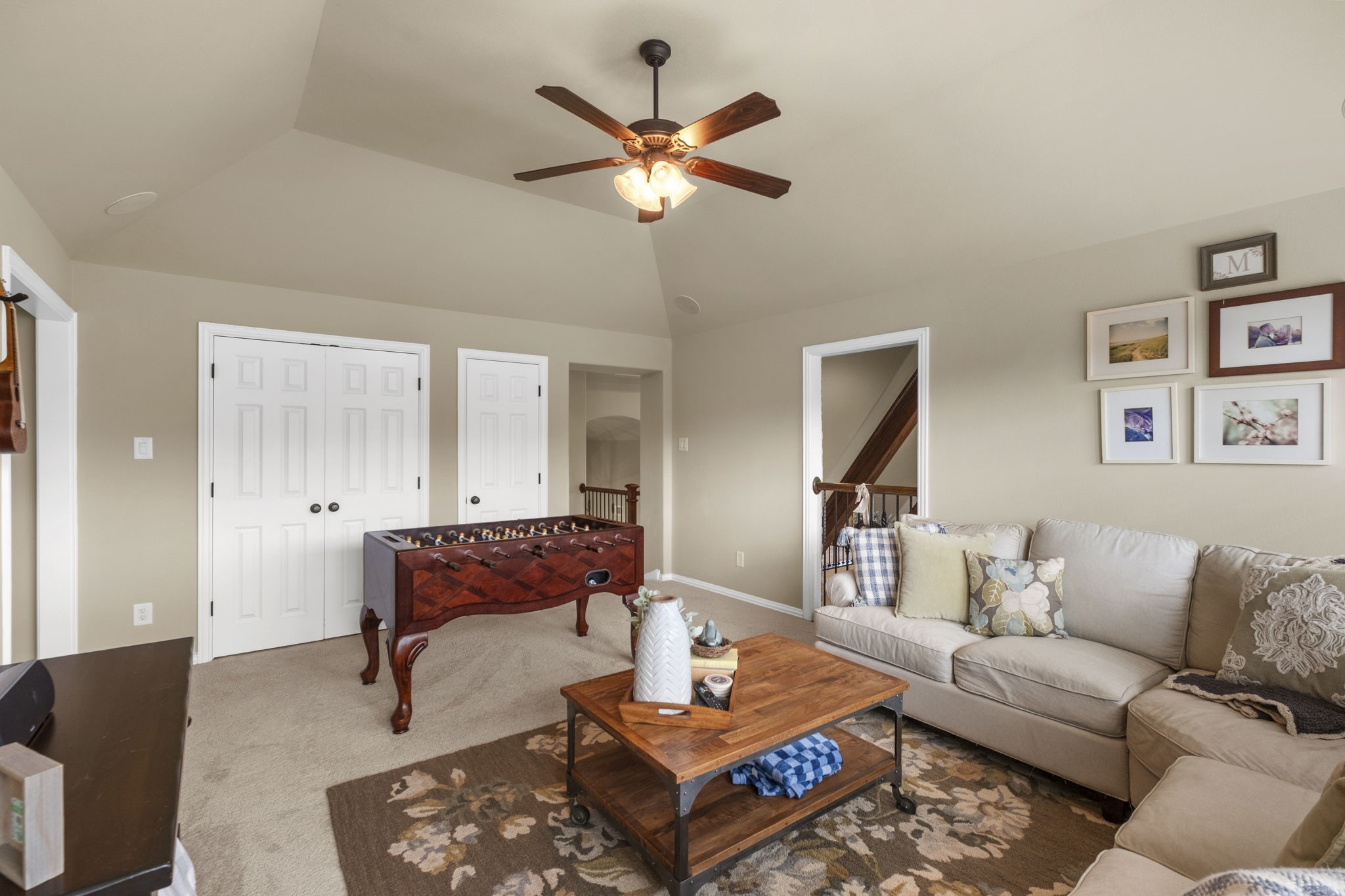 Alternate view of the spacious second-floor game room highlighting vaulted ceilings, multi-panel closet doors, direct access to the staircase landing area, and open flow for versatile layout options.