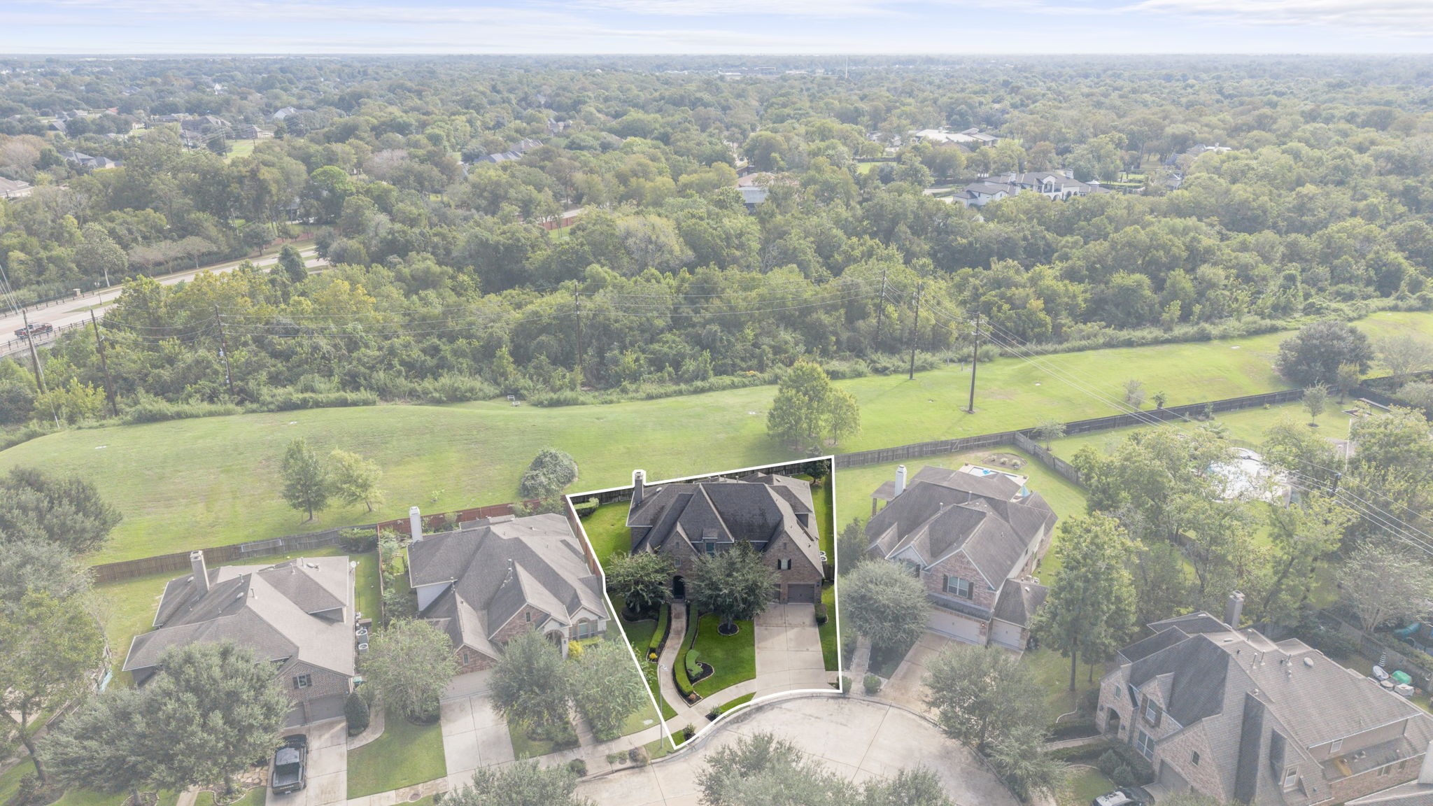 High-altitude aerial view highlighting the property line and lot boundaries set within a quiet cul-de-sac. Shows the expansive green reserve buffer running behind the private backyard and wood fencing.