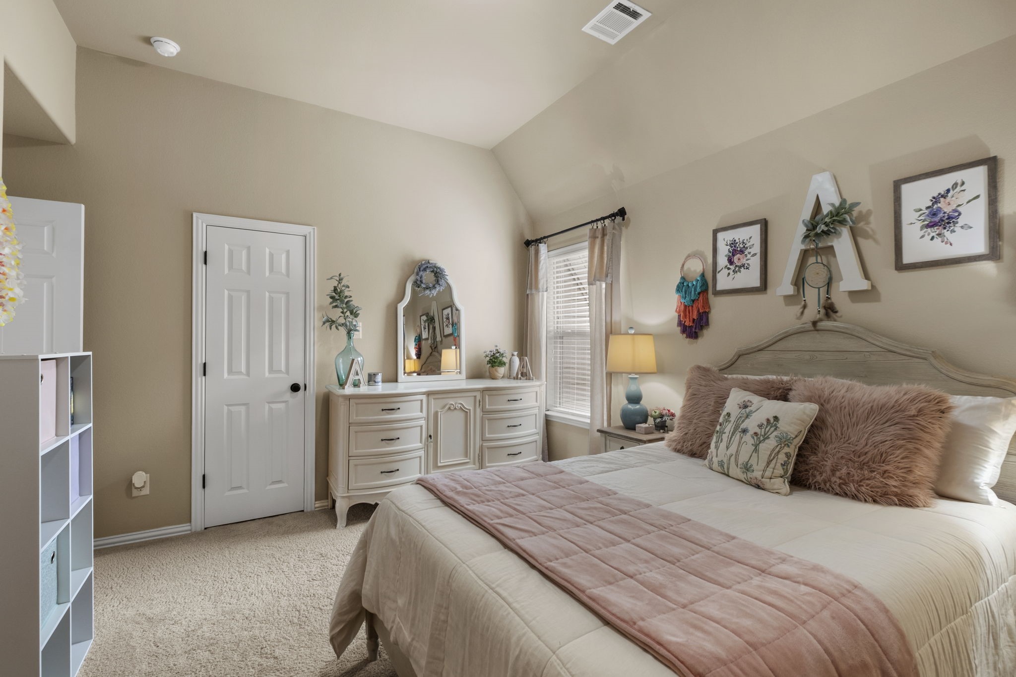 Charming upstairs secondary bedroom featuring vaulted ceilings, plush neutral carpeting, a double-hung window with blinds and drapery, a standard storage closet, and direct suite access.