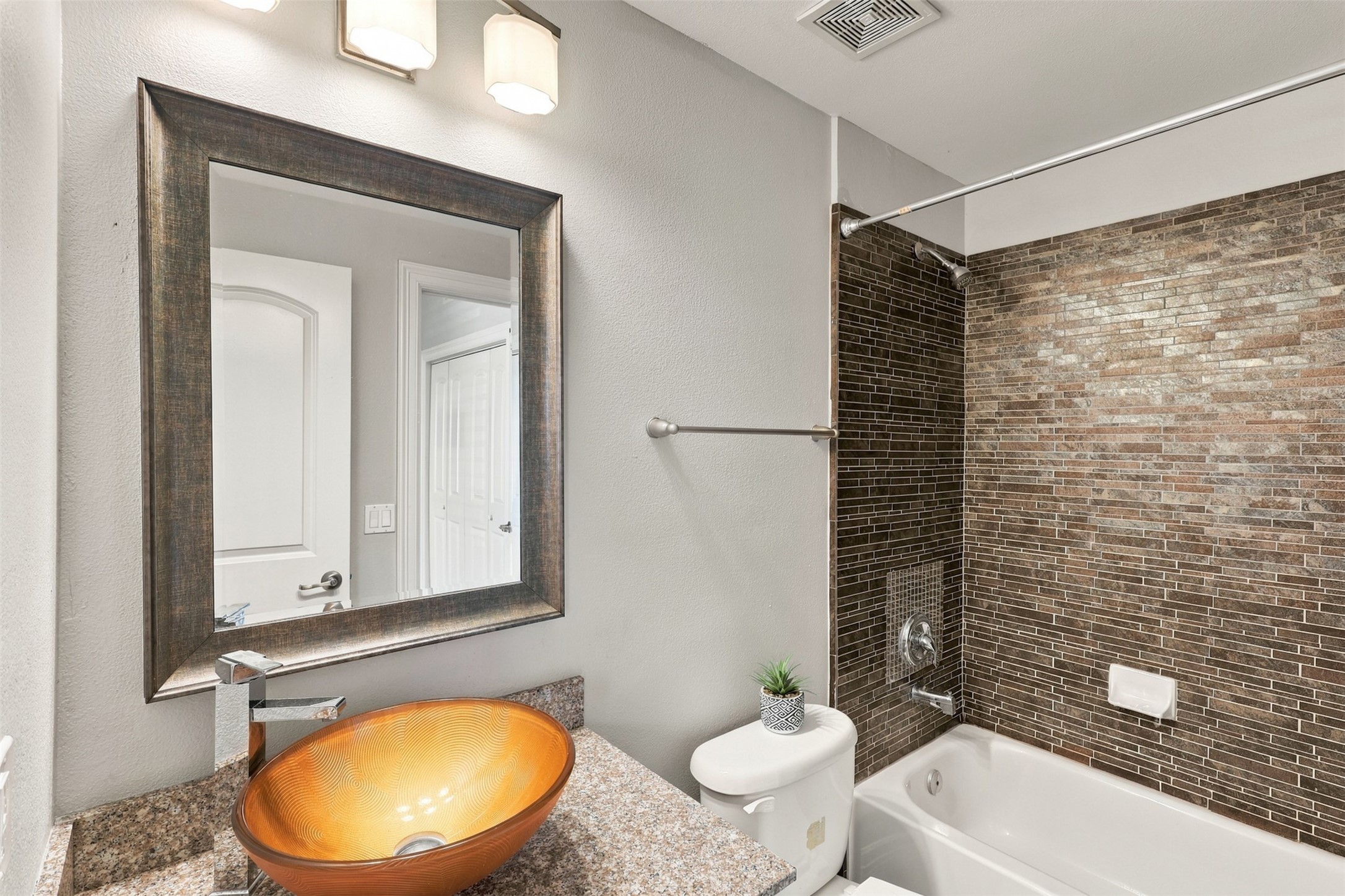 Stylish bathroom featuring a sleek vessel sink, elegant granite countertops, and a modern tile backsplash in the shower area.