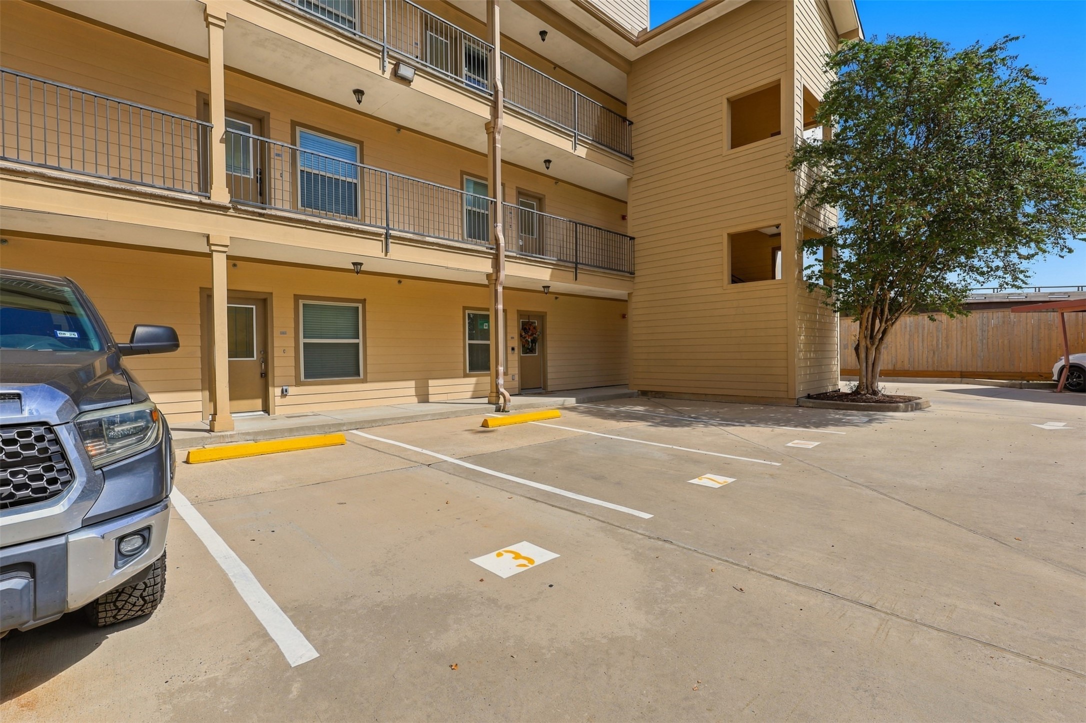 Convenient and spacious parking area adjacent to a well-maintained multi-level building, offering easy access and a welcoming entrance.