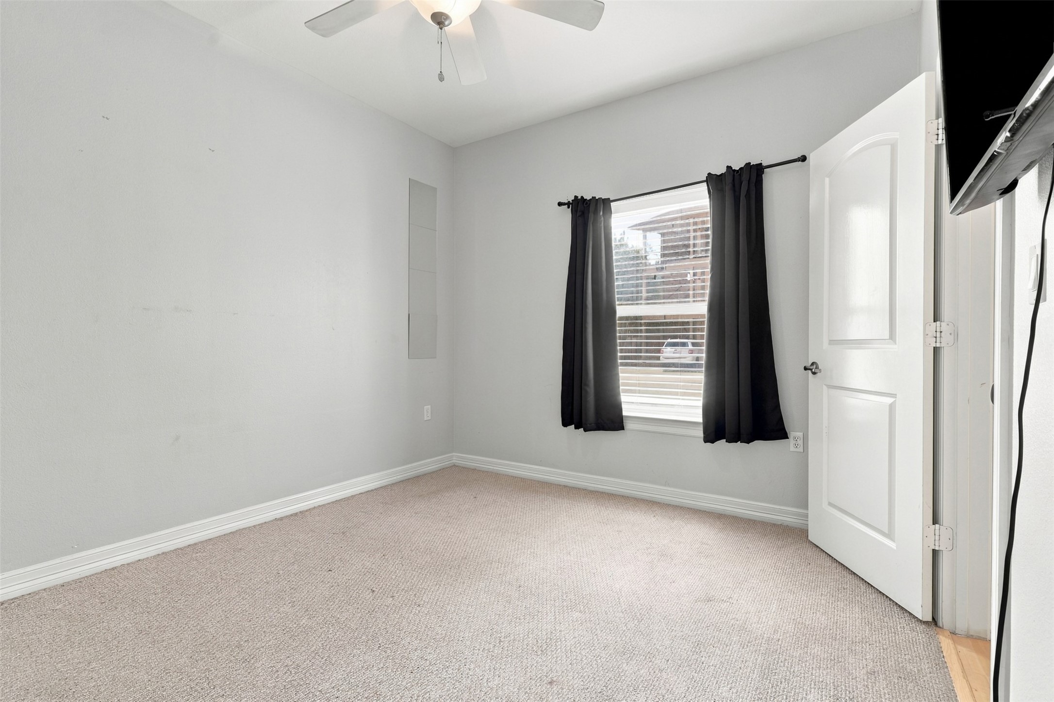Bright and inviting bedroom featuring neutral tones, plush carpeting, and a ceiling fan, offering comfort and style.