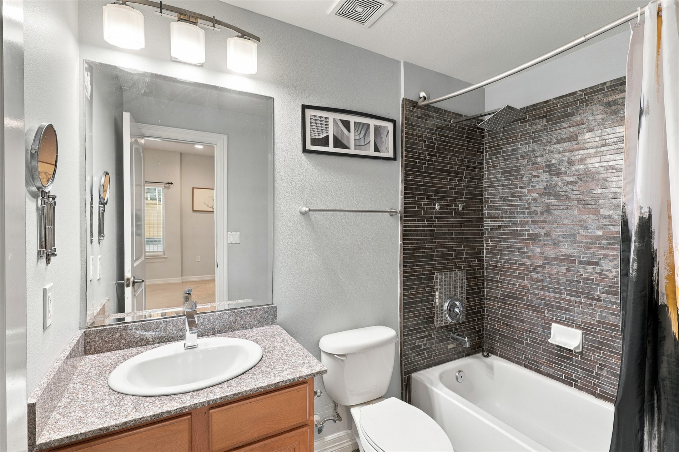 Modern bathroom featuring sleek dark tile, a granite countertop with a stylish sink, and ambient lighting.