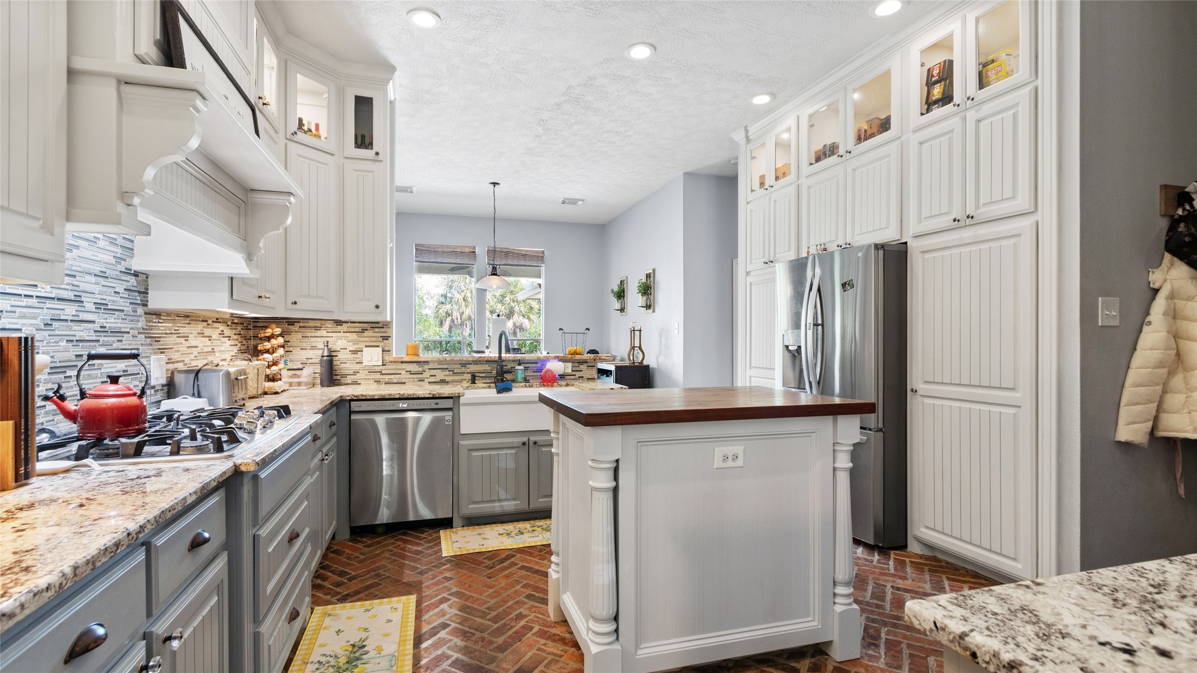 A butcher block island anchors the kitchen, while the brick flooring adds a unique touch of character.