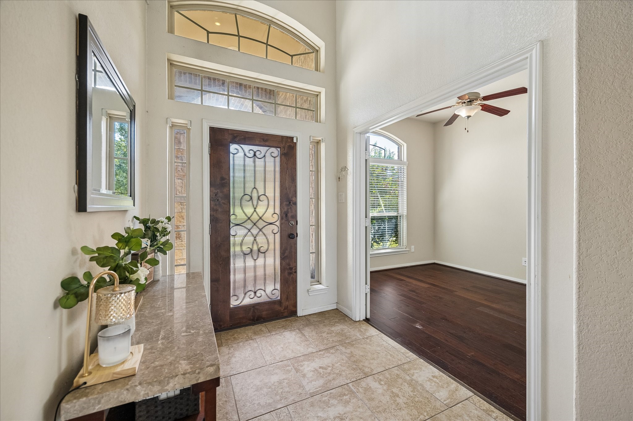 Stunning entryway featuring soaring ceilings, an elegant front door with decorative glass, and an abundance of natural light.  Seamlessly opens to the home office.