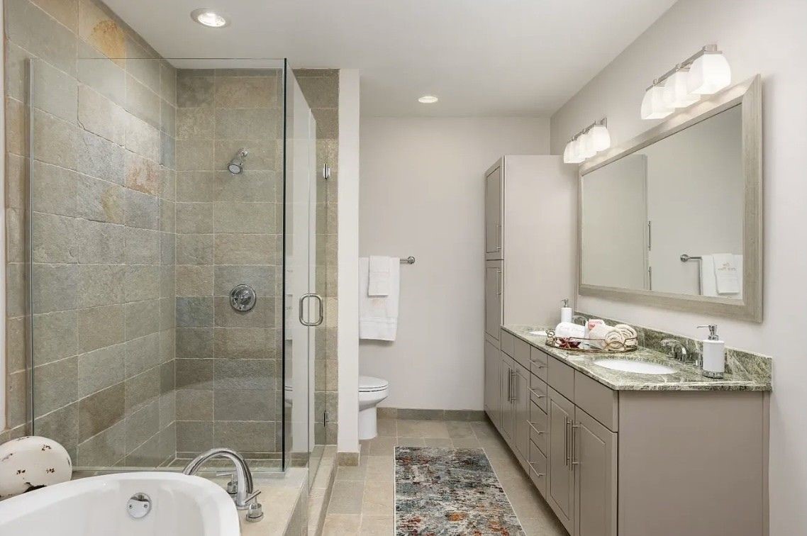 The luxurious primary bathroom is thoughtfully designed with a dual-sink vanity, granite countertops, abundant cabinet storage and contemporary finishes throughout. The spacious layout creates a bright, elegant retreat for everyday comfort and convenience.