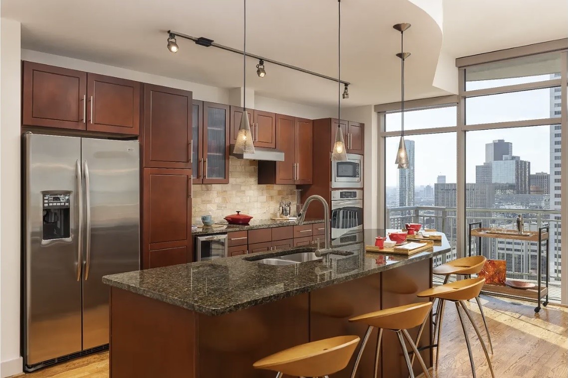 At the heart of the home, this beautifully appointed kitchen offers premium finishes, granite countertops, stainless steel appliances, a large island with bar seating and an included built-in wine chiller. The open layout and floor-to-ceiling windows seamlessly blend indoor living with spectacular downtown views.