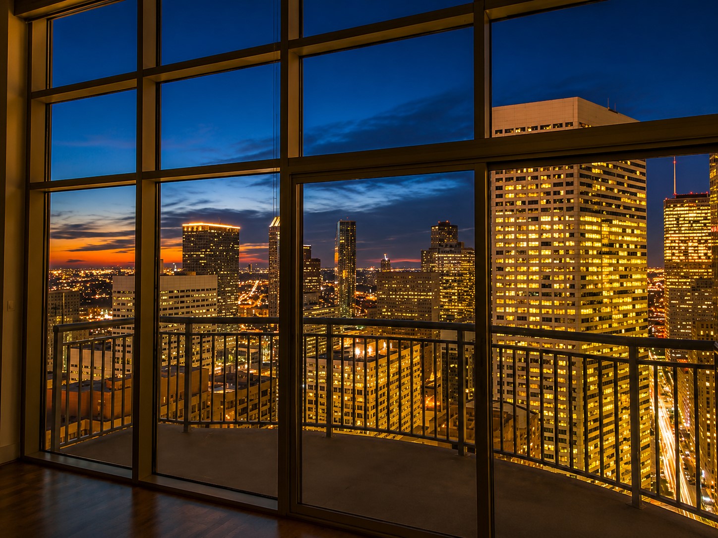 Breathtaking Downtown Houston views come alive at sunset, framed by dramatic floor-to-ceiling windows and a private balcony overlooking the illuminated city skyline. *Picture taken from the 31st floor