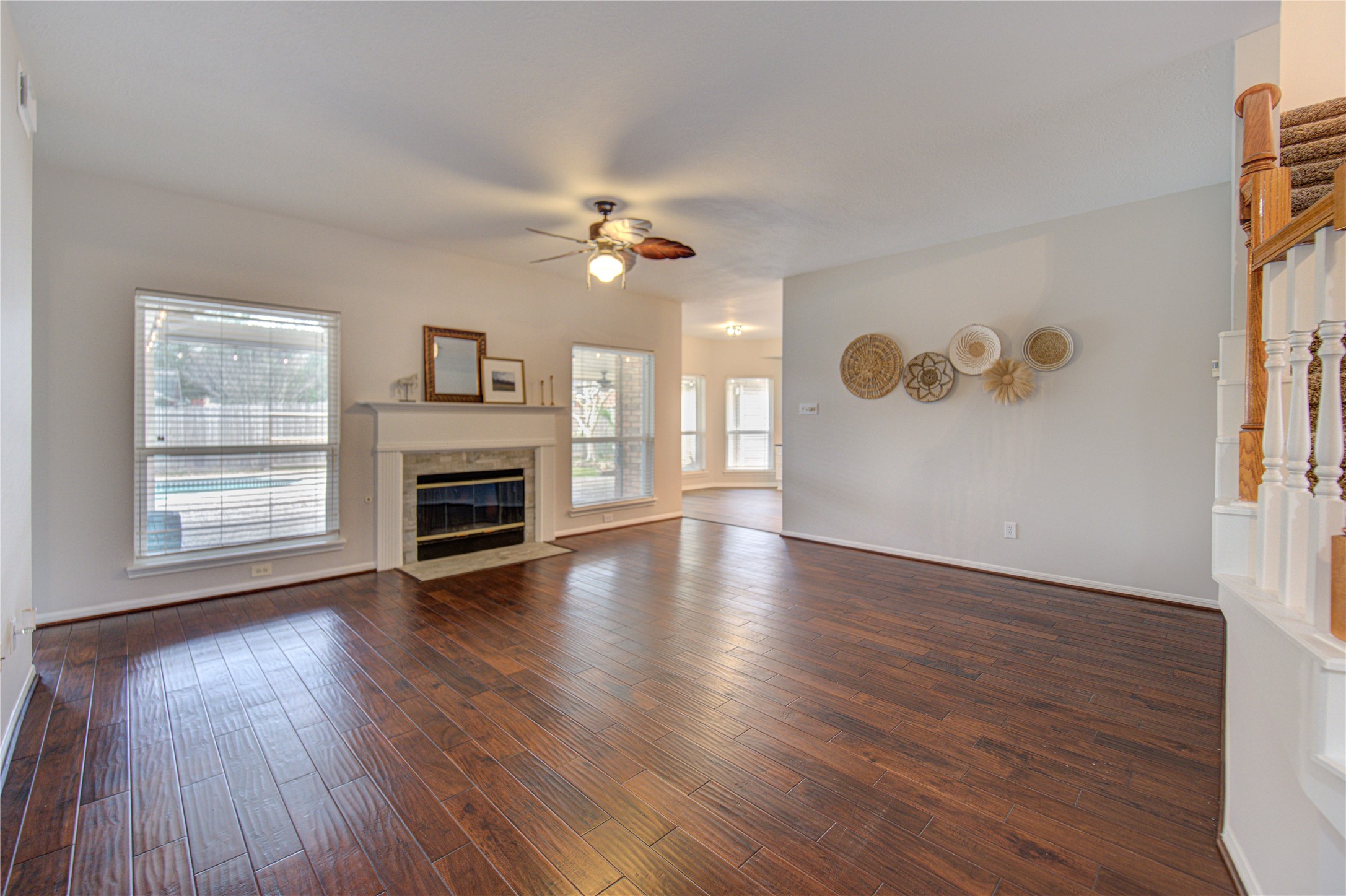 This inviting home features a spacious living area with rich hardwood floors, a cozy fireplace, and ample natural light. The elegant staircase with carpeted steps adds charm, leading to an upper level. Ideal for comfortable family living.