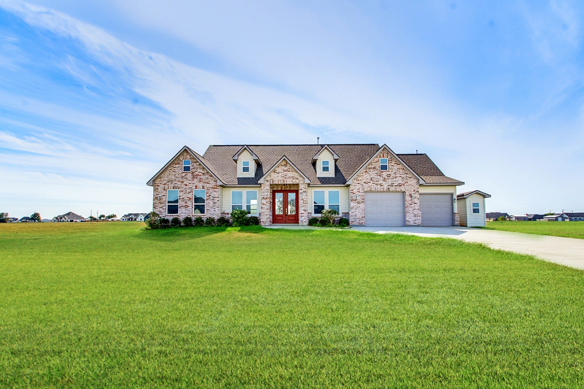 Charming 2389 sq.ft. brick ranch-style home with a spacious one-acre lot, inviting front entrance, and attached 549 sq.ft. two car garage, set against a picturesque sky.
