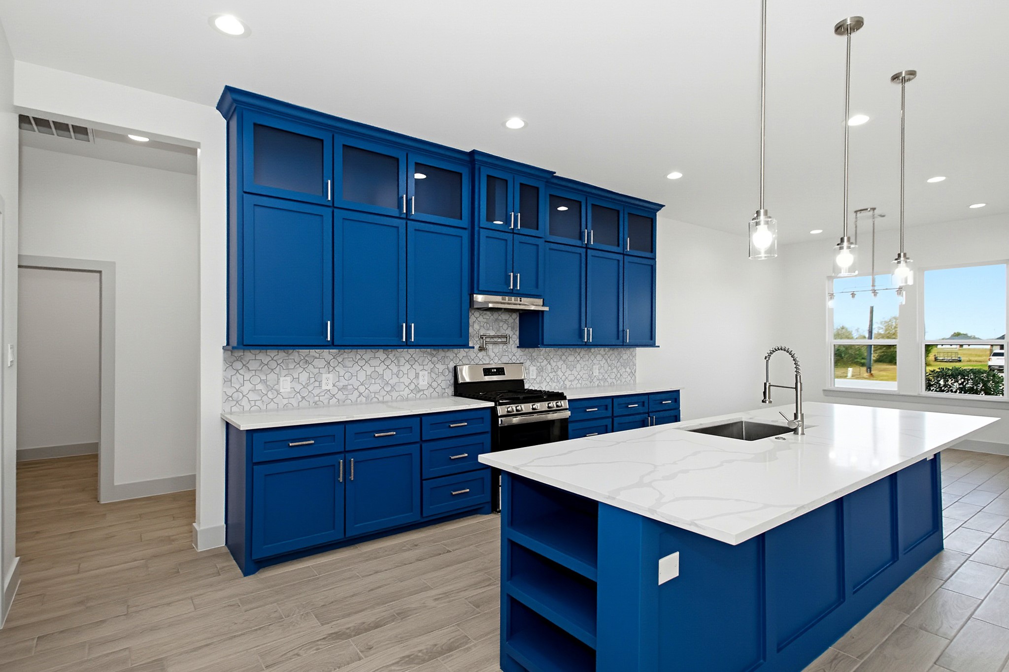 Stunning modern kitchen featuring bold blue cabinetry, sleek stainless steel appliances, and a spacious island with elegant pendant lighting and quartz countertops, perfect for entertaining.