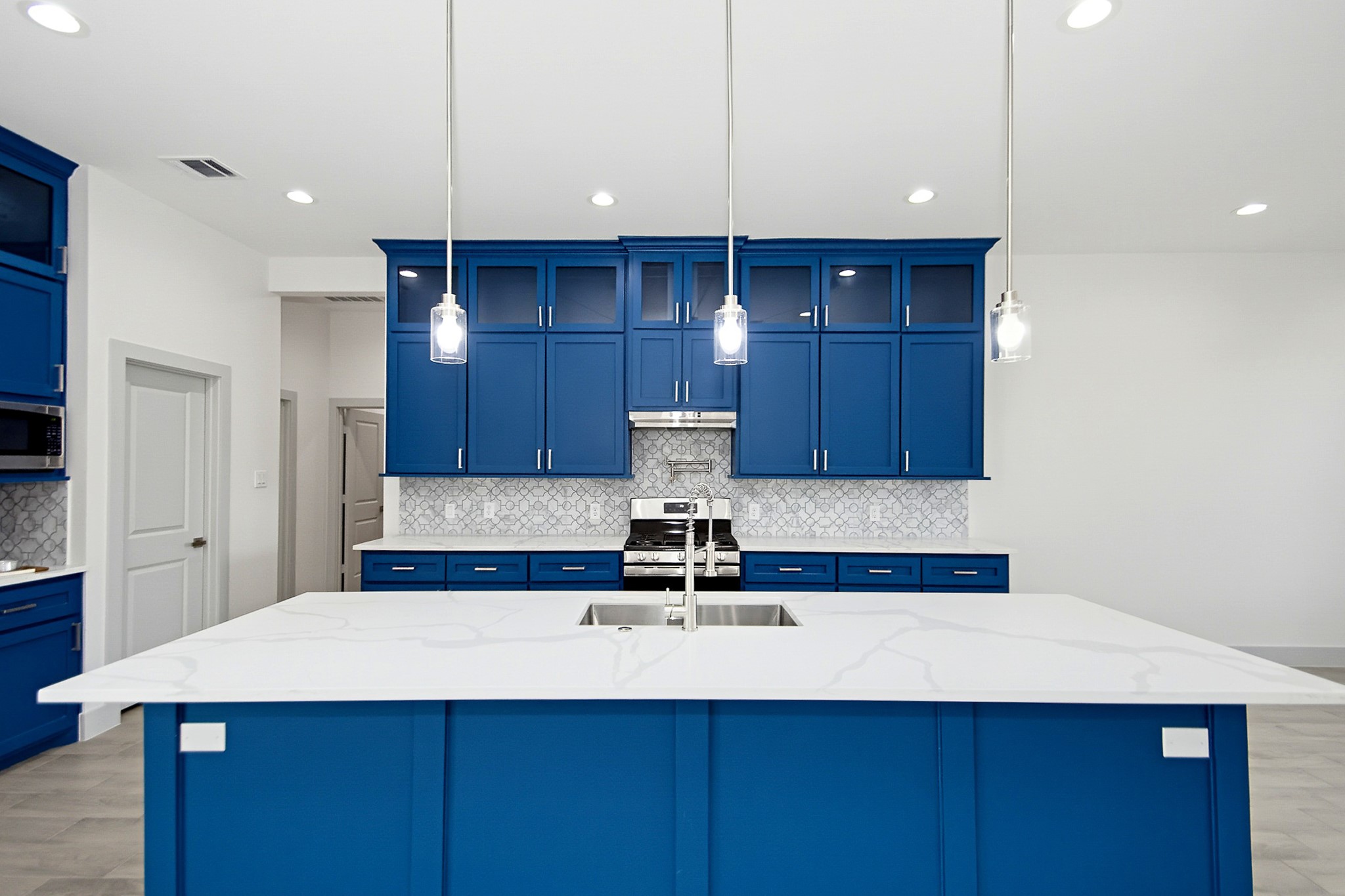 Stunning 19x14 kitchen with bold blue cabinetry, sleek quartz countertops, and modern pendant lighting, featuring a central island with a built-in sink.