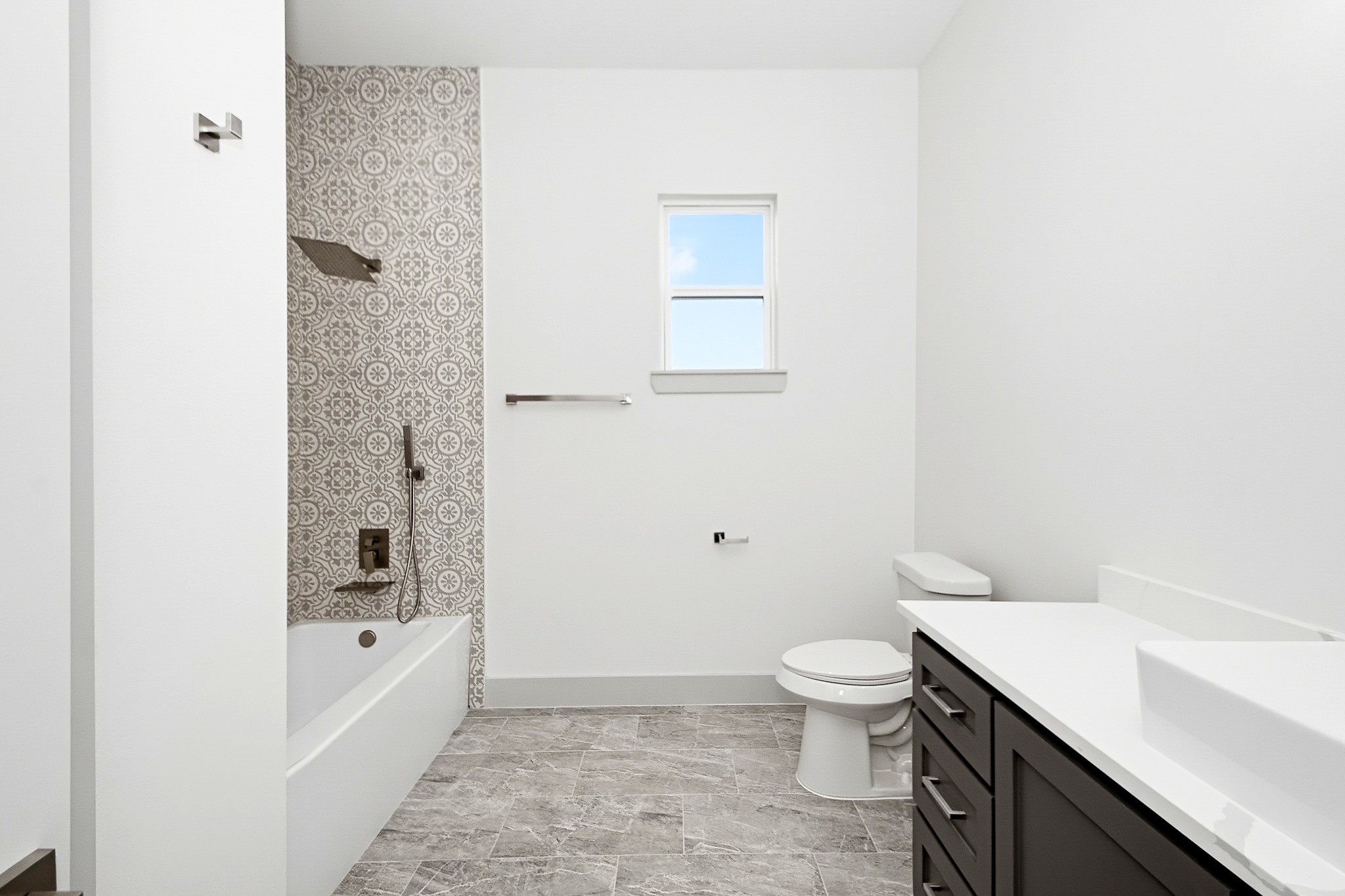 Elegant 10x10 secondary bathroom featuring a sleek vanity, patterned tile accents, and a bathtub with modern fixtures.
