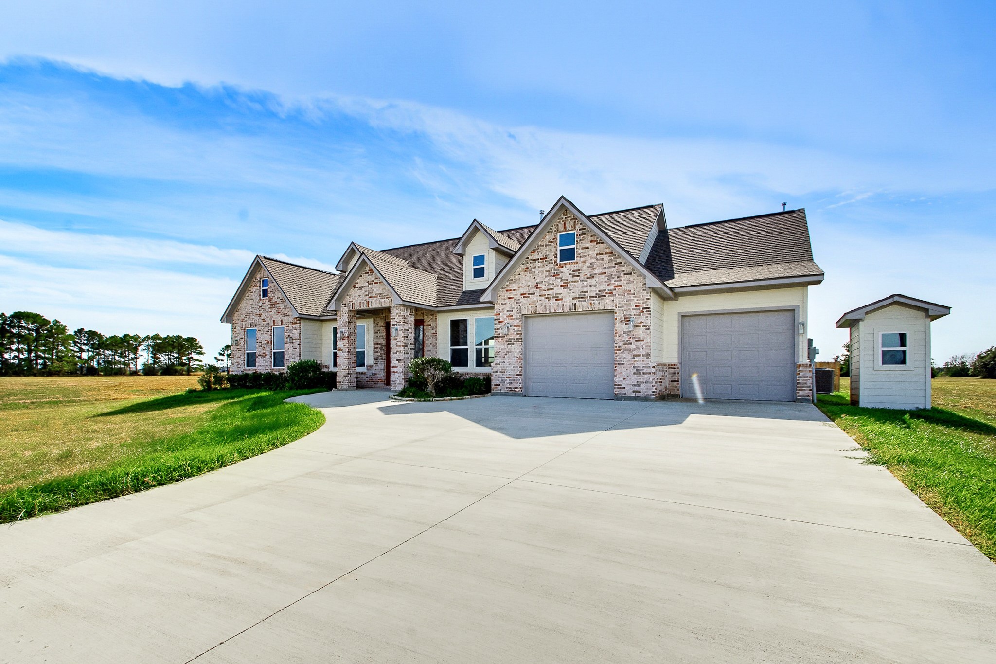 Charming 2389 sq.ft. brick home with a spacious 549 sq.ft. two-car garage, nestled on a sprawling one-acre lot with beautiful open fields and clear blue skies.