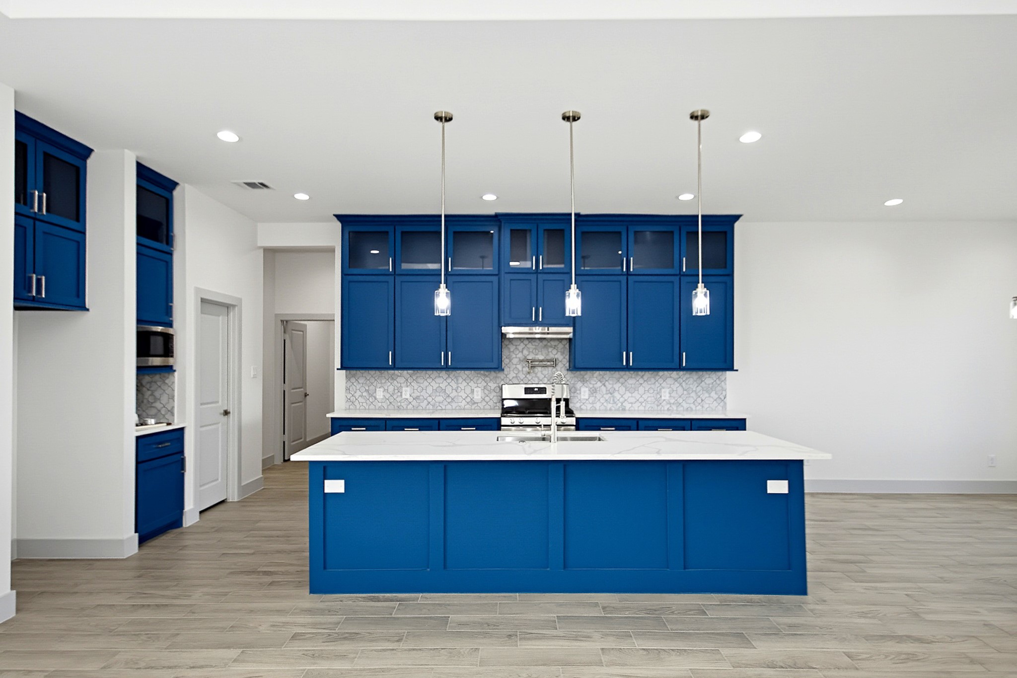 Stunning modern kitchen with vibrant blue cabinetry, sleek quartz countertops, and stylish pendant lighting, creating a perfect blend of elegance and functionality.