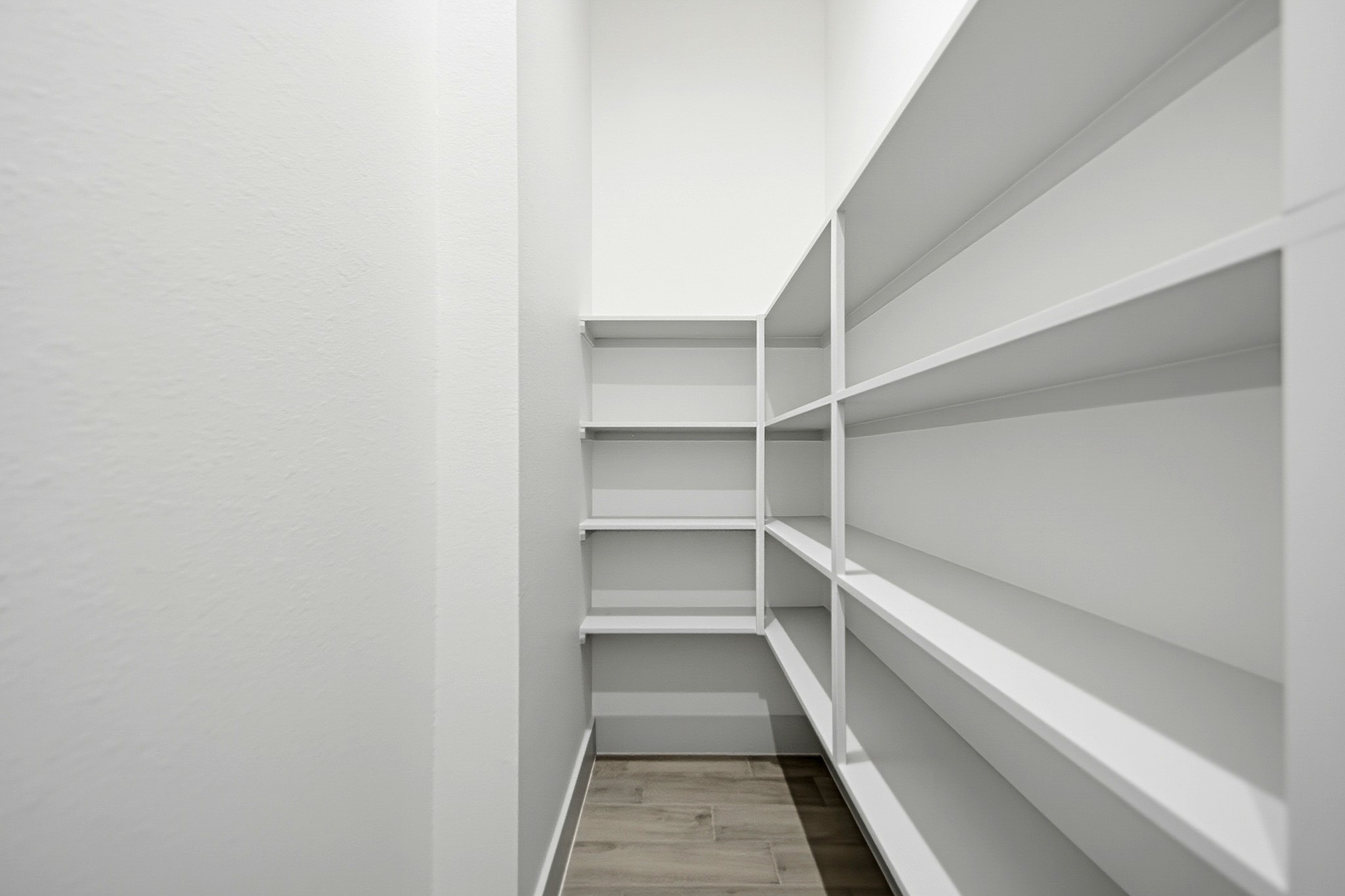 Spacious walk-in pantry with ample shelving for all your storage needs. The space continues to the left side for more storage space.