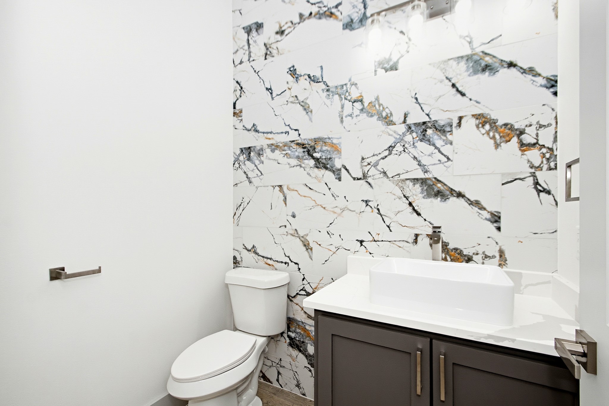 Elegant half bathroom featuring a striking marble-patterned accent wall, modern vanity, and sleek fixtures for a sophisticated touch.