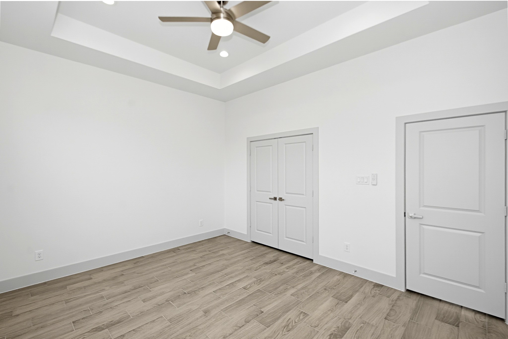 14.5x12 Second bedroom double door closet, modern ceiling fan and a stylish tray ceiling for added charm and sophistication.