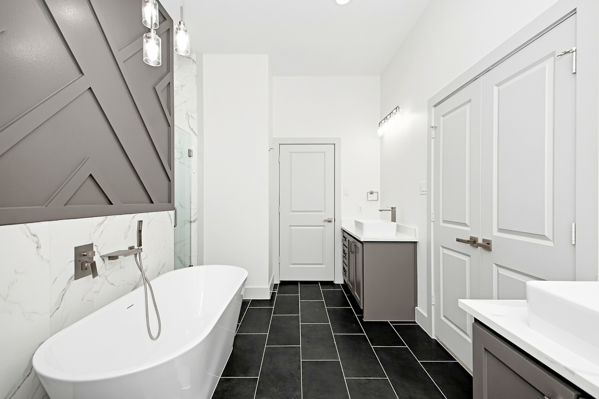 Luxurious primary 16x12 bathroom featuring a sleek freestanding bathtub, modern fixtures, and stylish geometric accent wall, complemented by elegant black tile flooring and dual vanities.