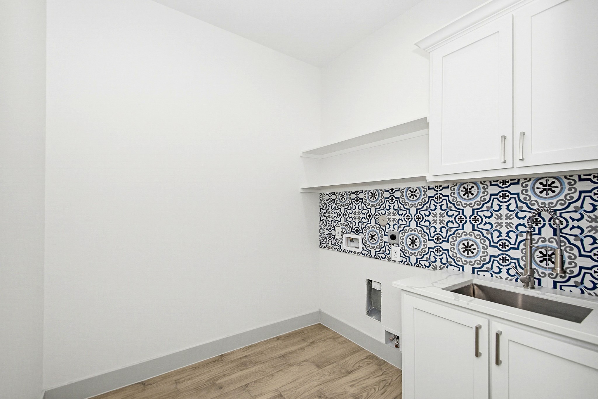 Sleek laundry 8x 8 laundry room featuring elegant white cabinetry, a modern sink, and vibrant patterned tiles, complemented by warm tile flooring.