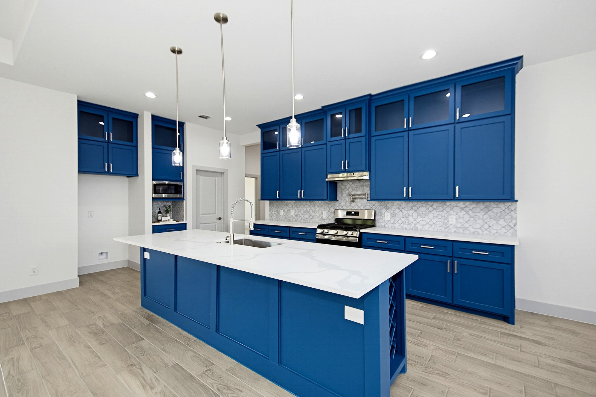 A modern 19x14 kitchen featuring vibrant blue cabinetry, sleek stainless-steel appliances, and elegant pendant lighting over a spacious island with a white quartz countertop.