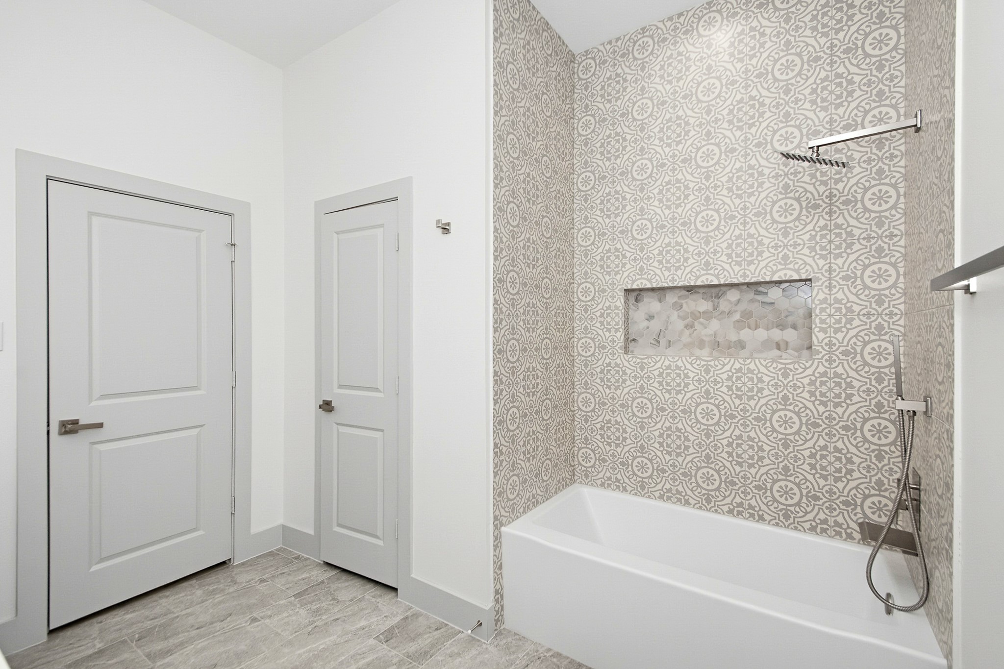 Elegant 10x10 secondary bathroom featuring a stylish patterned tile wall, modern fixtures, and a sleek bathtub with built-in shelving.