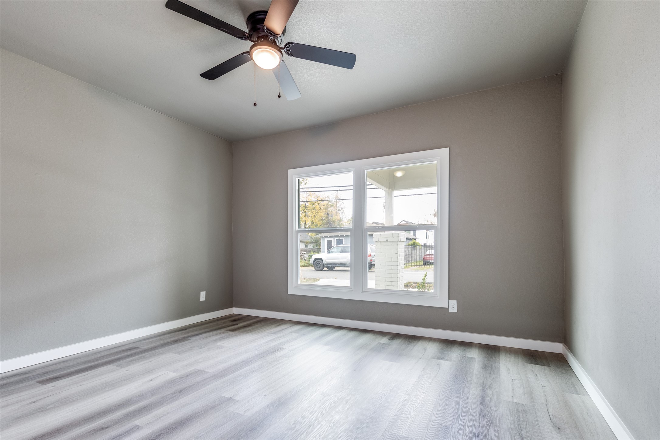 Sunny bedroom with new flooring, ceiling fan, and a calm neutral palette, perfect for a guest room, office, or flex space.