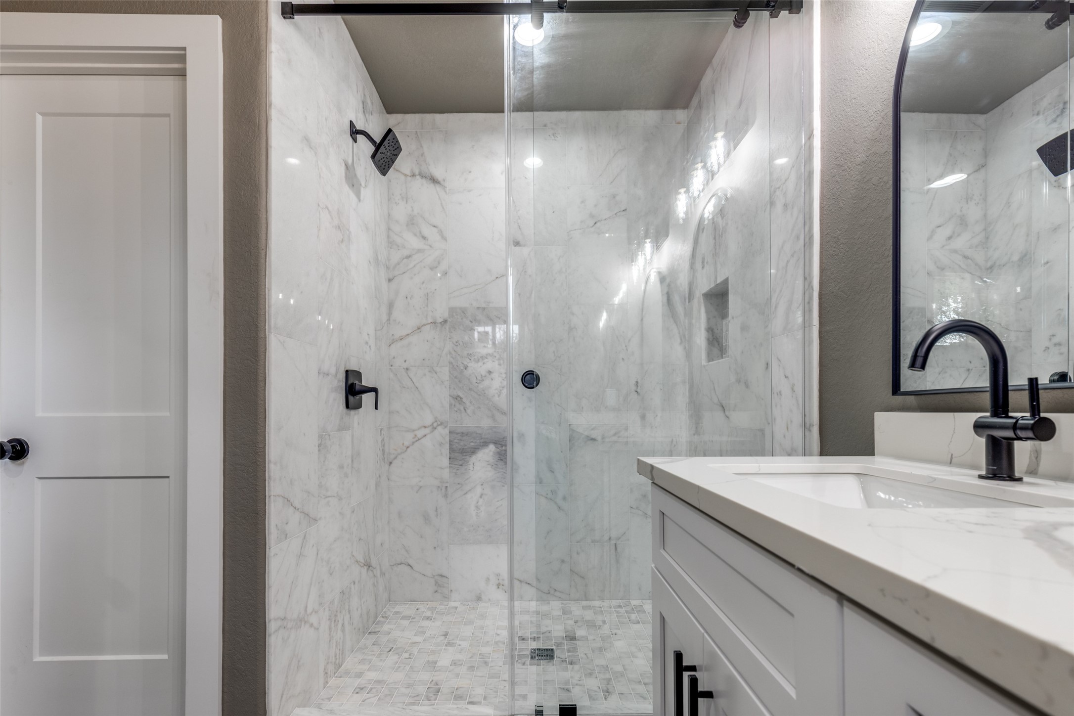 Statement shower with marble, sleek hardware, and a clean modern vanity that feels straight out of a boutique hotel.