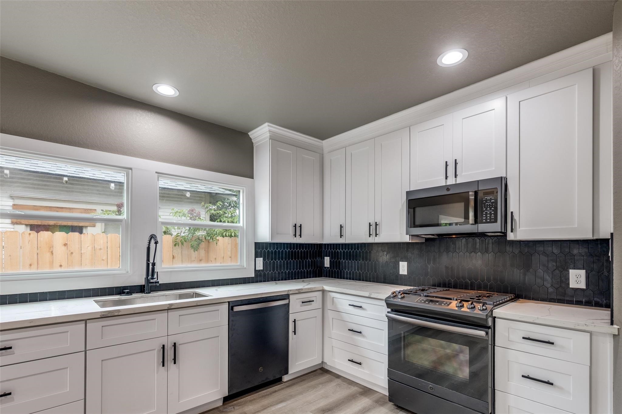 Classic white kitchen with real style and storage, featuring black stainless steel appliances and easy flow to the living space. Classic white kitchen with real style and storage, featuring black stainless steel appliances and easy flow to the living space.