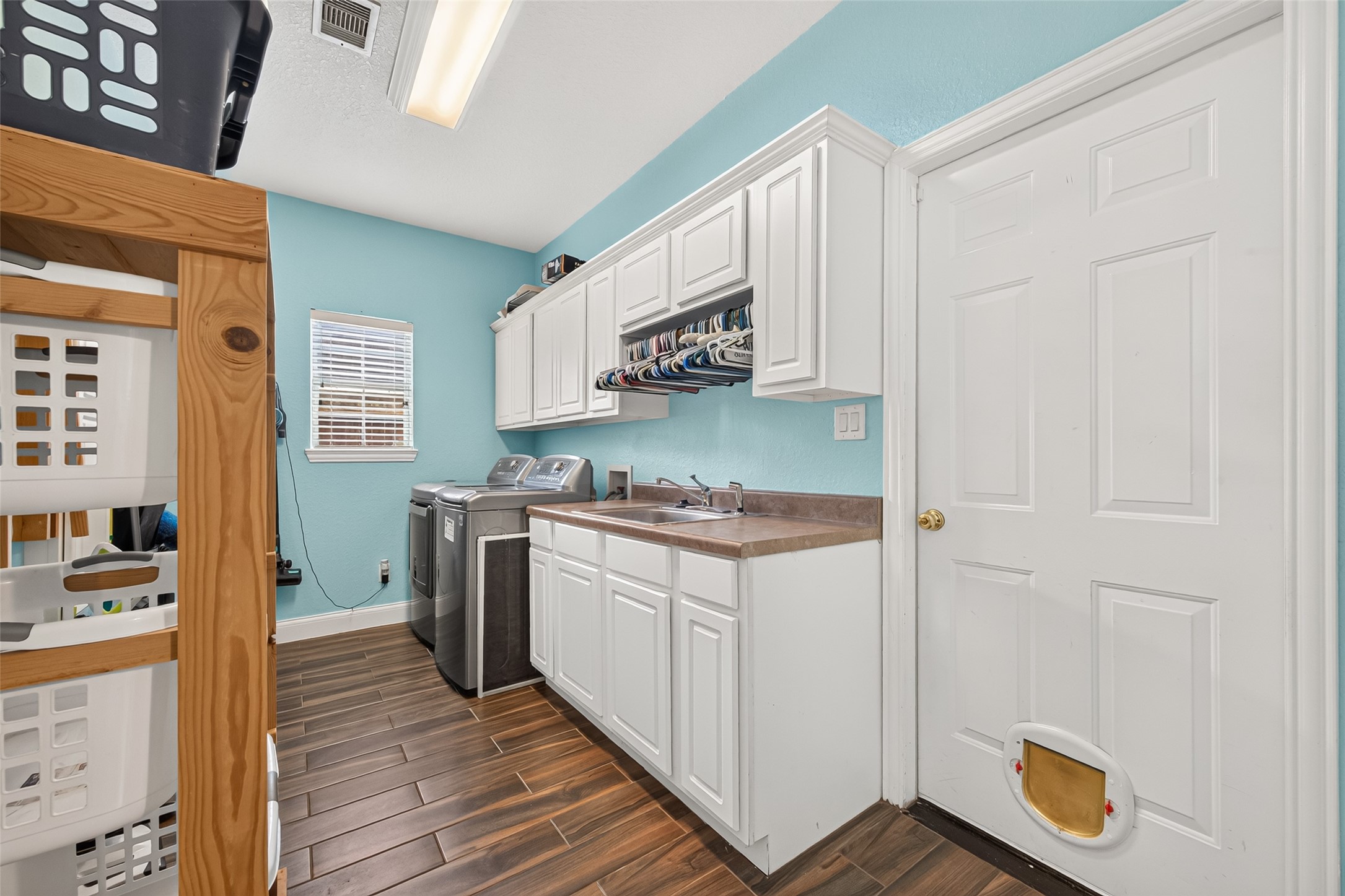 Laundry day made easier! This spacious laundry room features abundant cabinetry, generous counter space, a utility sink, and convenient access to the half bath and garage.