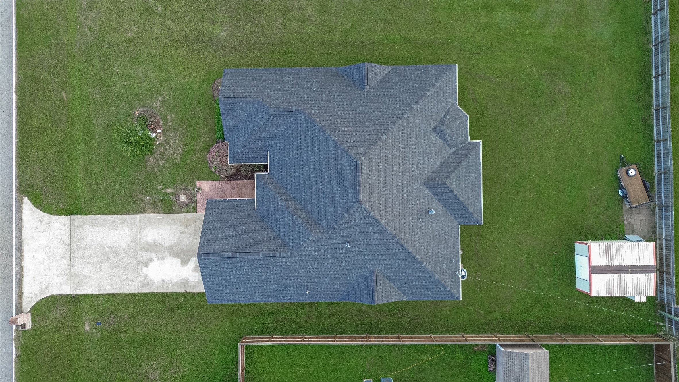 Bird's-eye view showcasing the home's roofline, driveway, and spacious backyard with detached storage shed