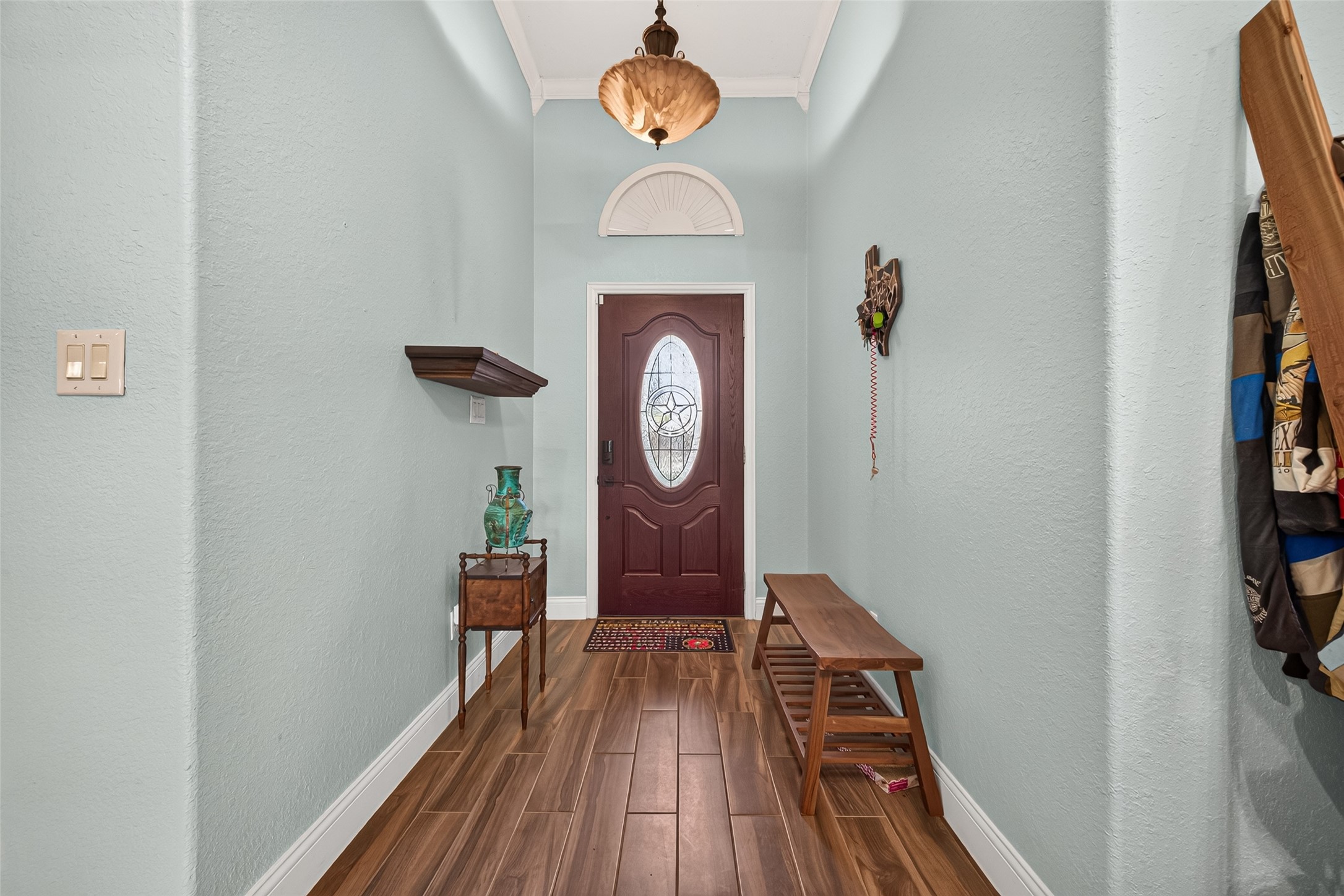 Step inside to a spacious entry hall featuring beautiful flooring, soft blue walls, and decorative lighting that creates a welcoming first impression.
