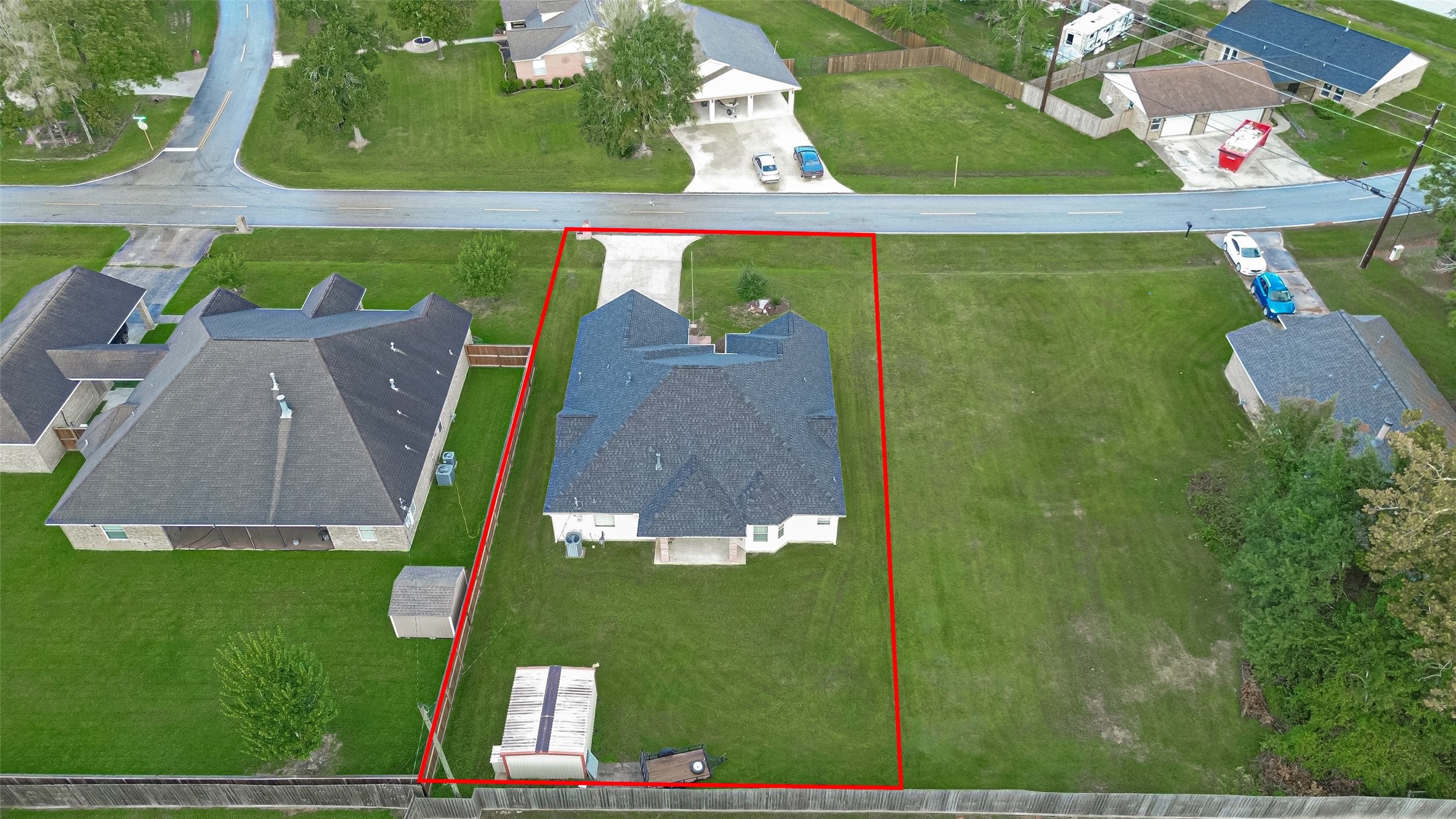 Overhead view highlighting the property's generous lot size, fenced backyard, covered patio, and surrounding neighborhood.