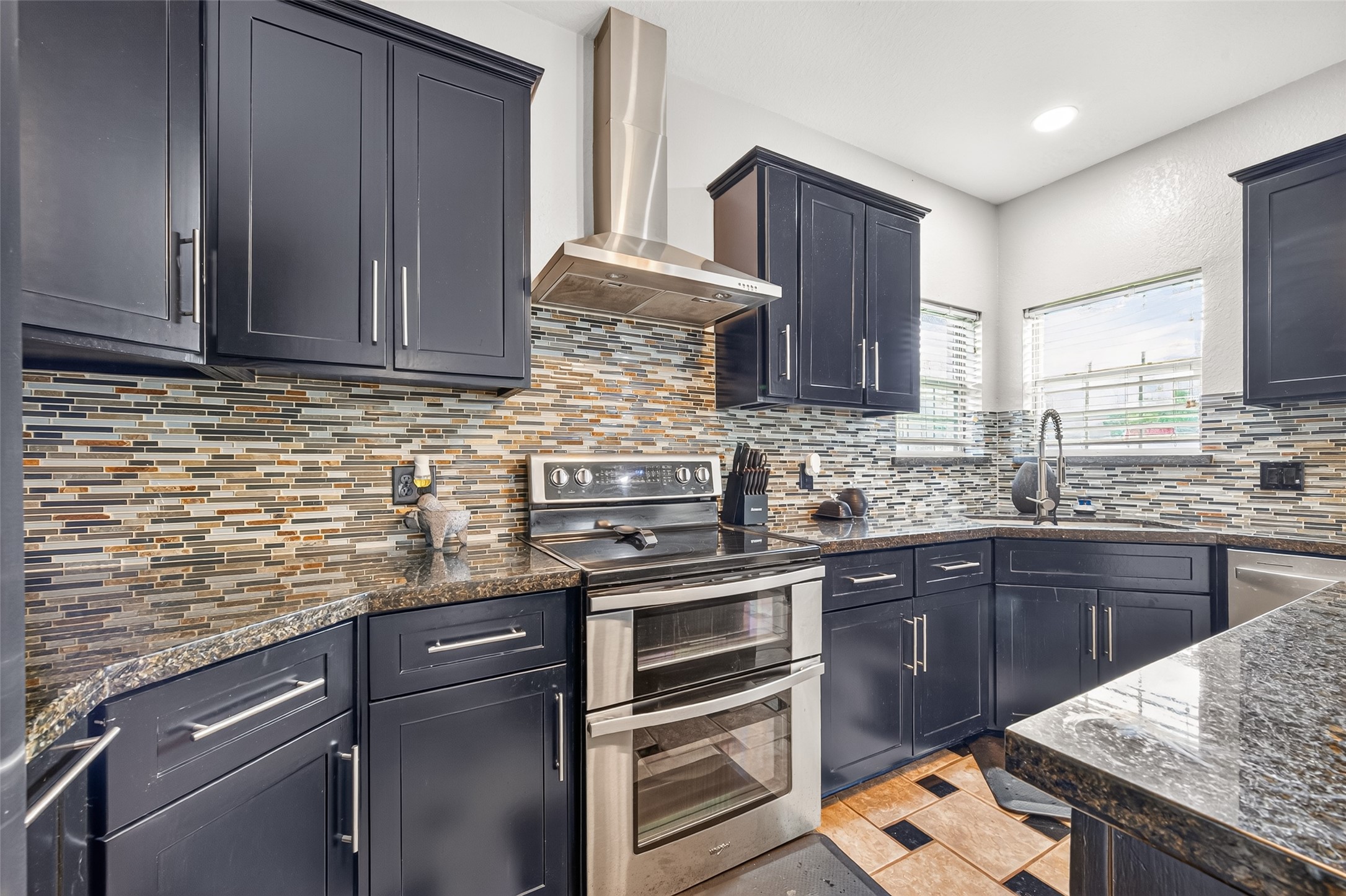 A closer look at the kitchen's stainless steel appliances, decorative backsplash, and modern cabinetry.