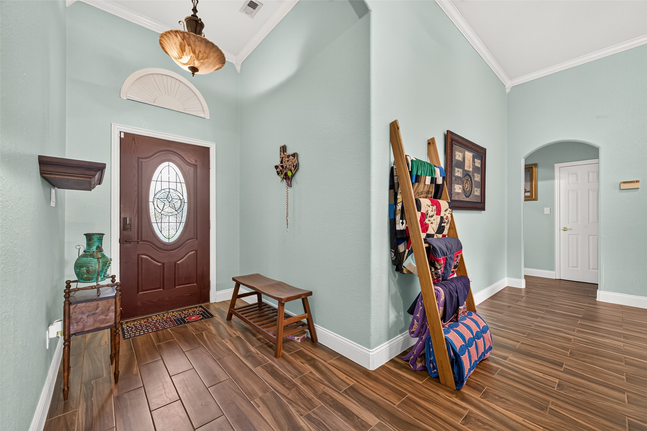 Another look at the welcoming foyer, showcasing its open feel, beautiful flooring, and graceful arched openings leading into the adjoining rooms.