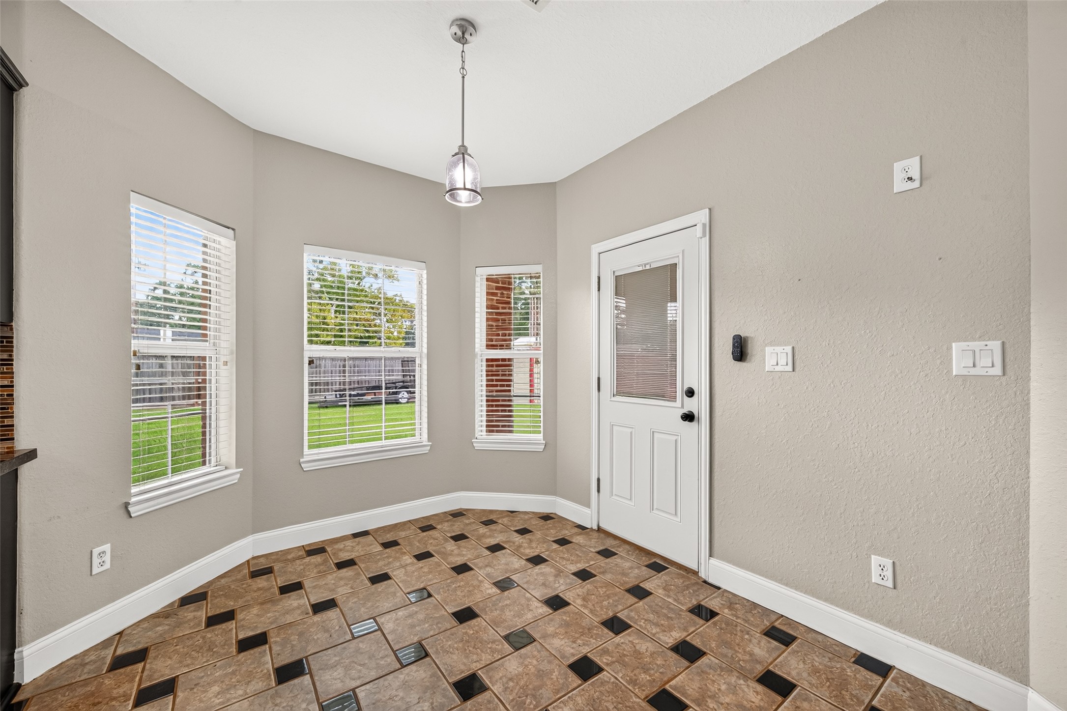 Bright and inviting breakfast area featuring beautiful windows, decorative tile flooring, and convenient access to the backyard. The perfect spot to enjoy your morning coffee!
