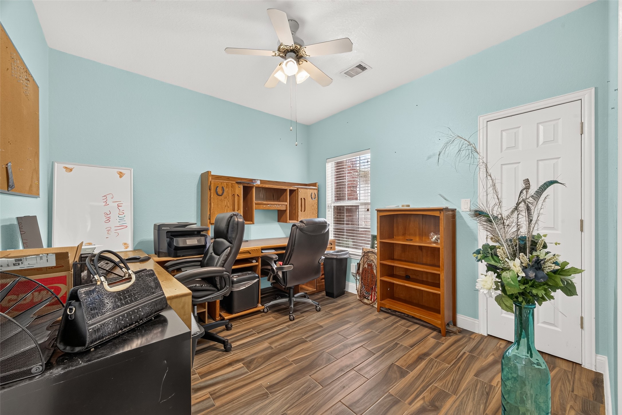 Versatile third bedroom currently used as a home office! Featuring beautiful wood-look flooring, a ceiling fan, and natural light, this flexible space can easily accommodate a bedroom, office, or hobby room.