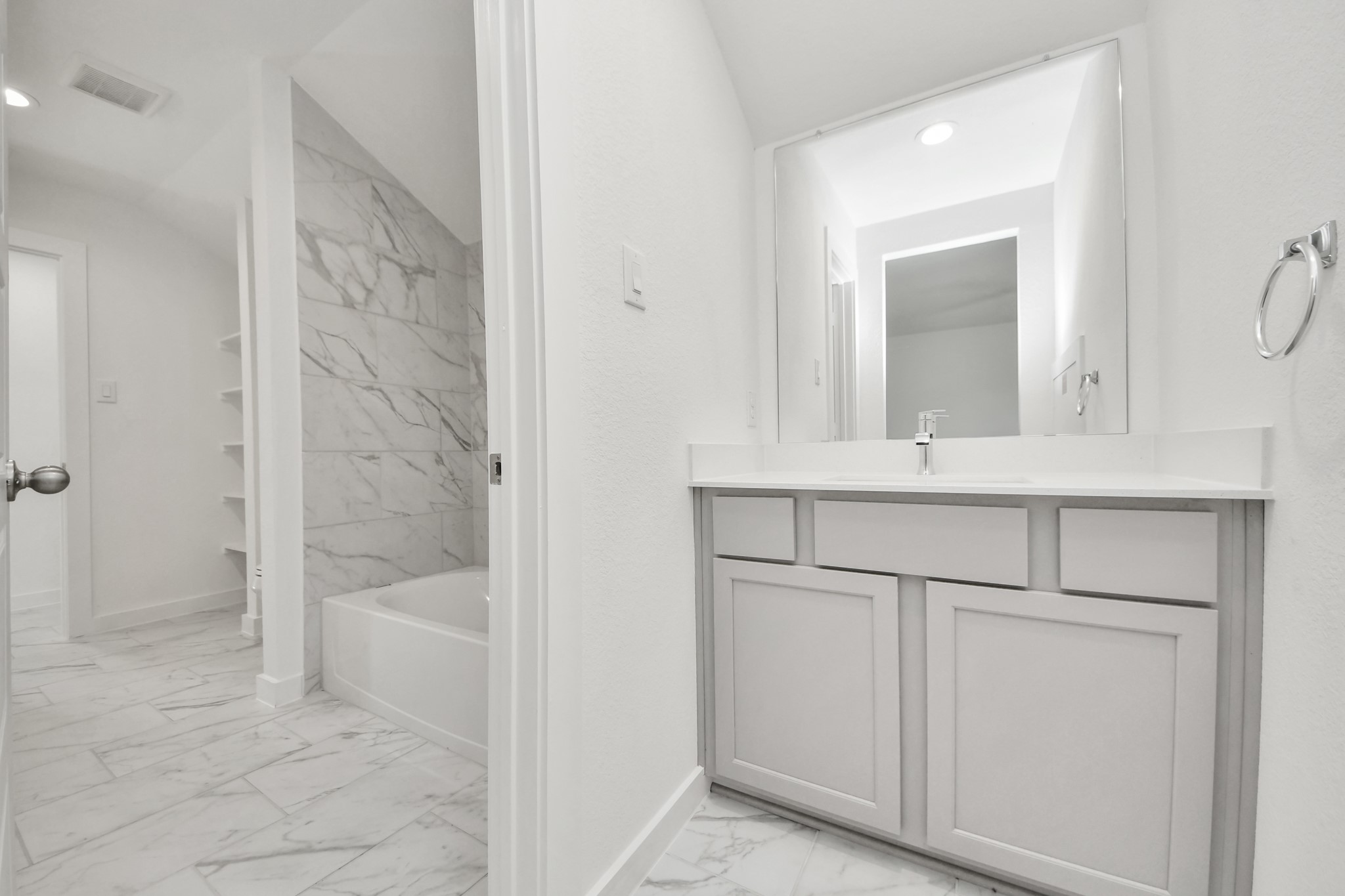 Experience convenience in the secondary bathroom, designed for Jack and Jill arrangements, now with a separate vanity area. This well-appointed space showcases stylish tile flooring, a bath/shower combo with an elegant tile surround, and light-stained wood cabinets. The beautiful light countertop adds a touch of sophistication, combining functionality and aesthetics seamlessly.