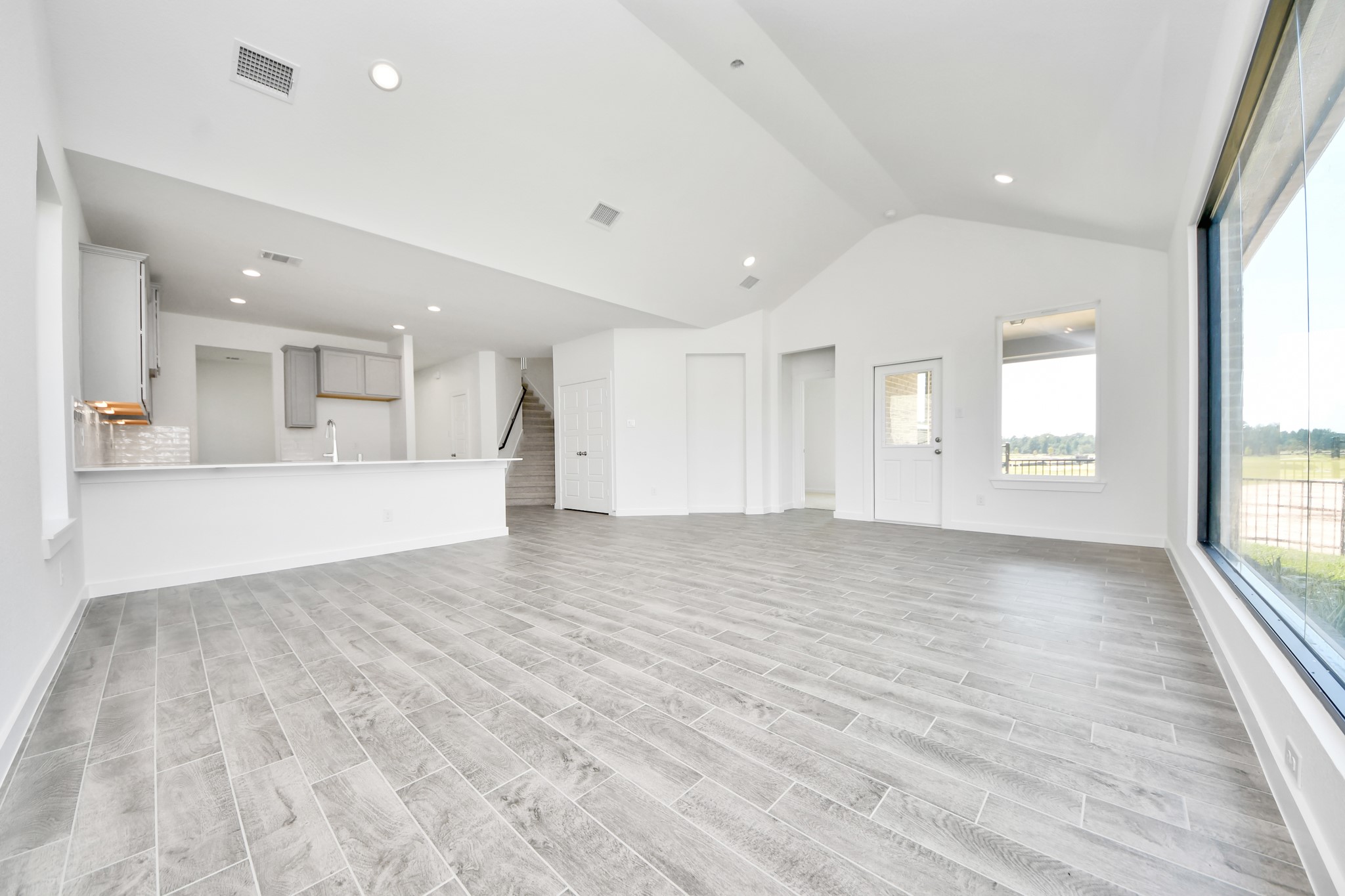 Welcome family and guests to your charming living room! With its high ceilings, recessed lighting, ceiling fan, custom paint, beautiful flooring, and large windows that let in abundant natural light, this room is perfect for gatherings.