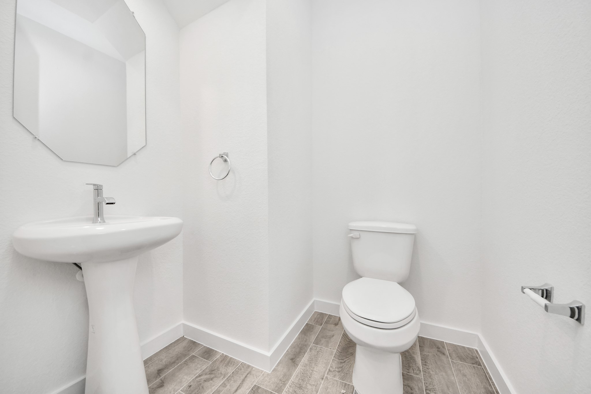 This half bathroom features a stylish pedestal sink, modern hardware, and bright recessed lighting, creating a sleek and inviting space.