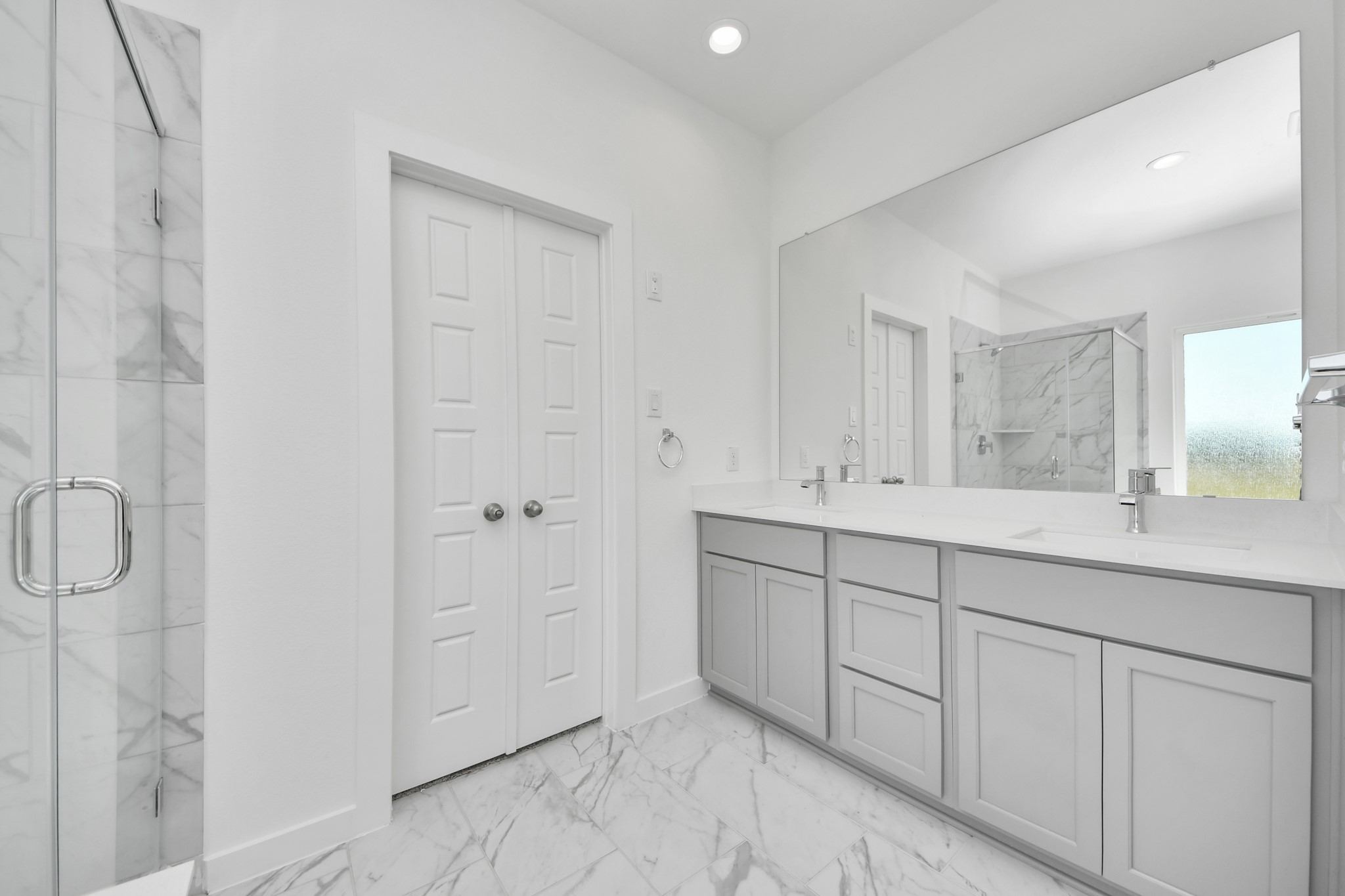 Elevate your daily routine at the elegant vanity, now equipped with double sinks, light countertops, modern hardware, and beautiful recessed lights.